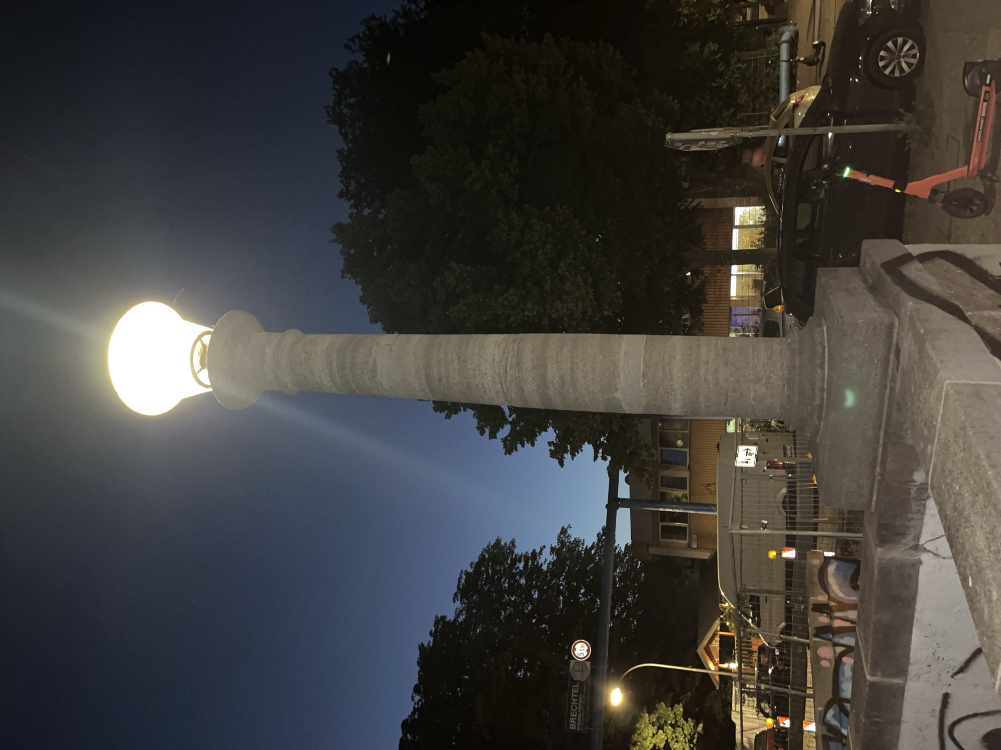 Ornate lamppost lights up a Berlin street at dusk