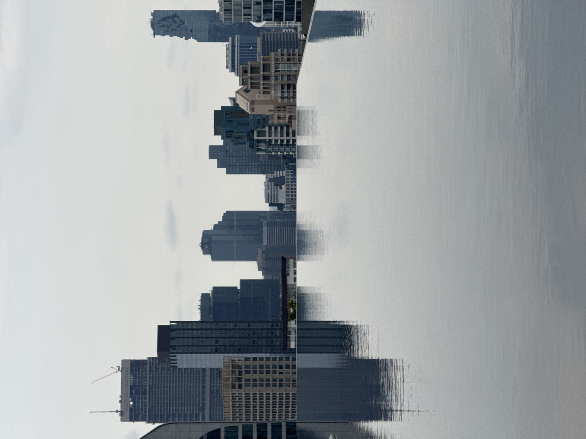 Bangkok skyline reflections captured in water during hazy morning