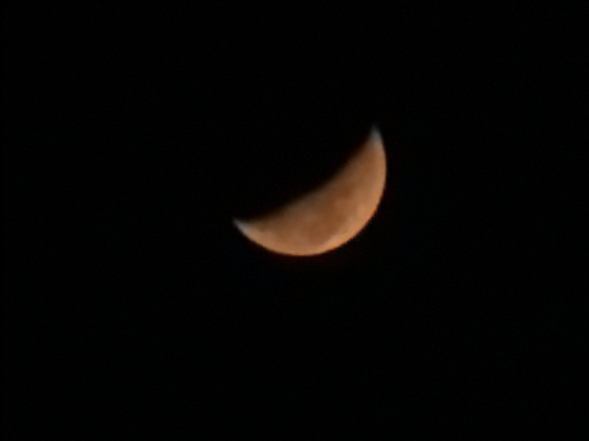Orange crescent moon over Vernon Hills on a summer night
