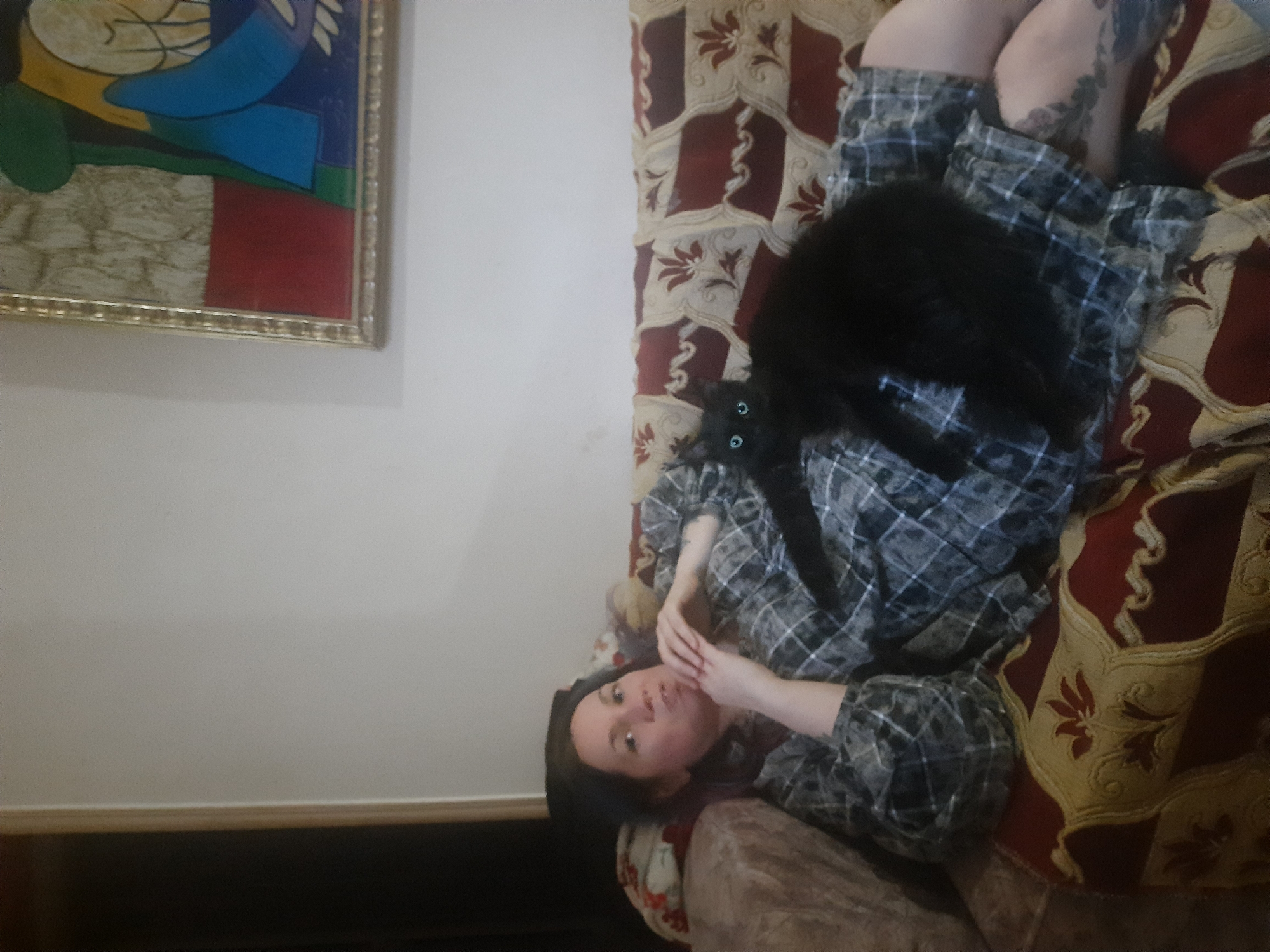 Woman relaxes with black cat on sofa in Al Hadaba
