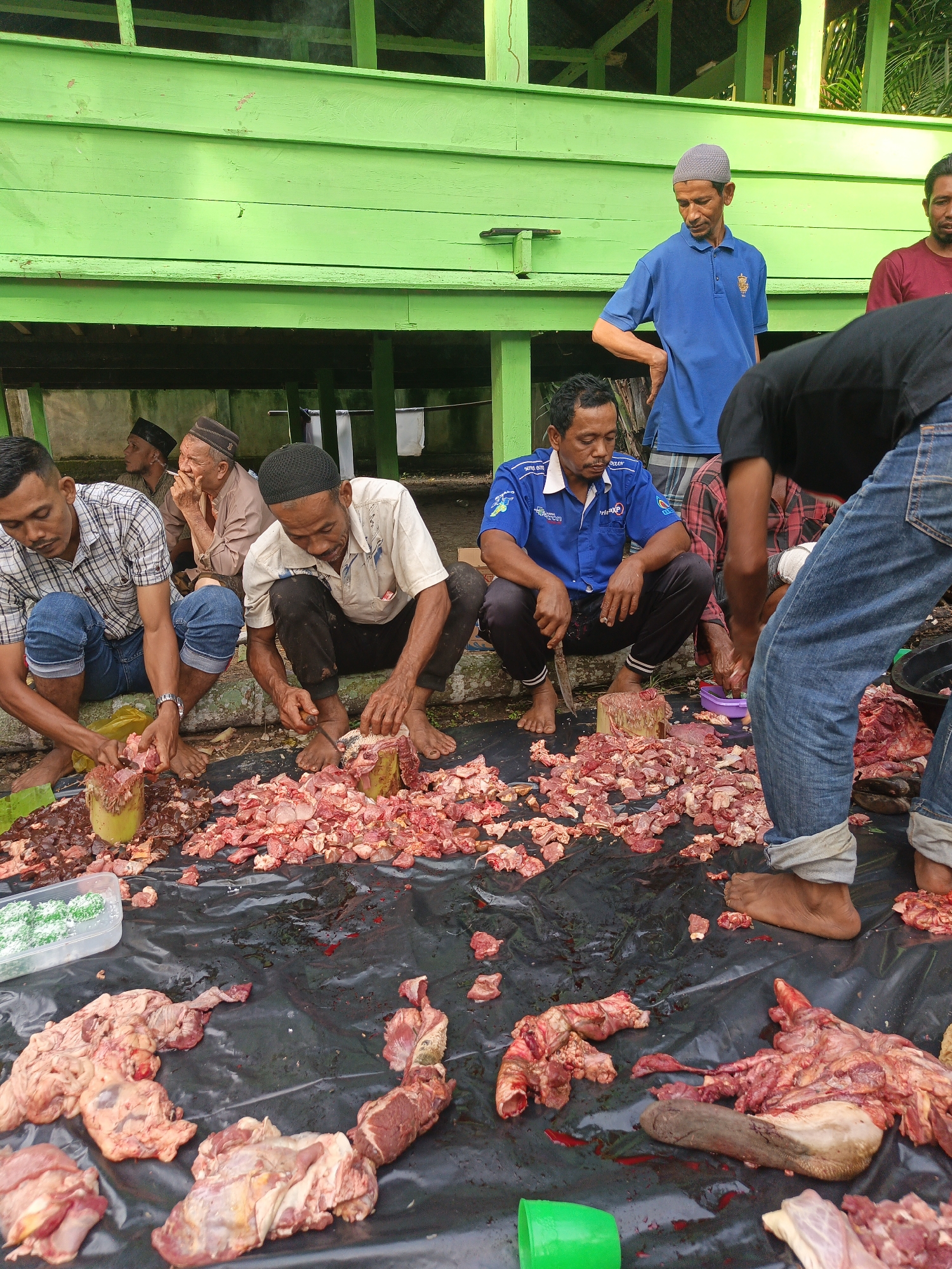 Communal cooking and meat prep at an outdoor gathering in Payakambuk