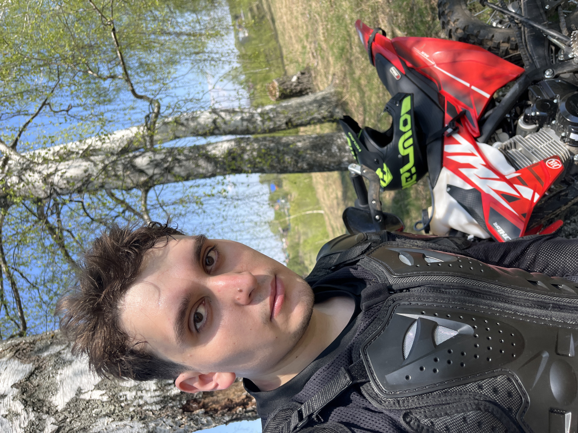 Motorcyclist poses with bike in Russian countryside spring scene