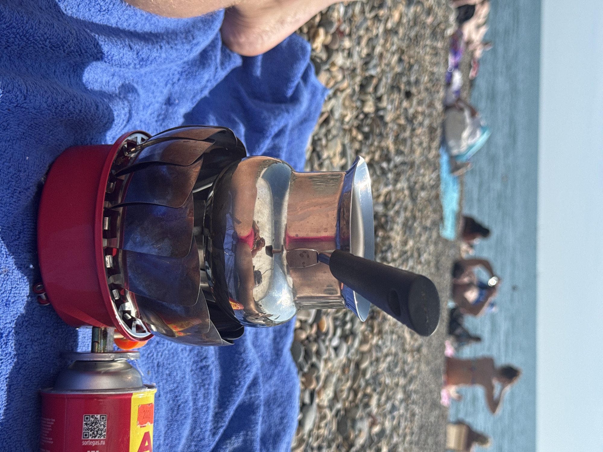 Beachgoer brews coffee on portable stove at Sochi beach