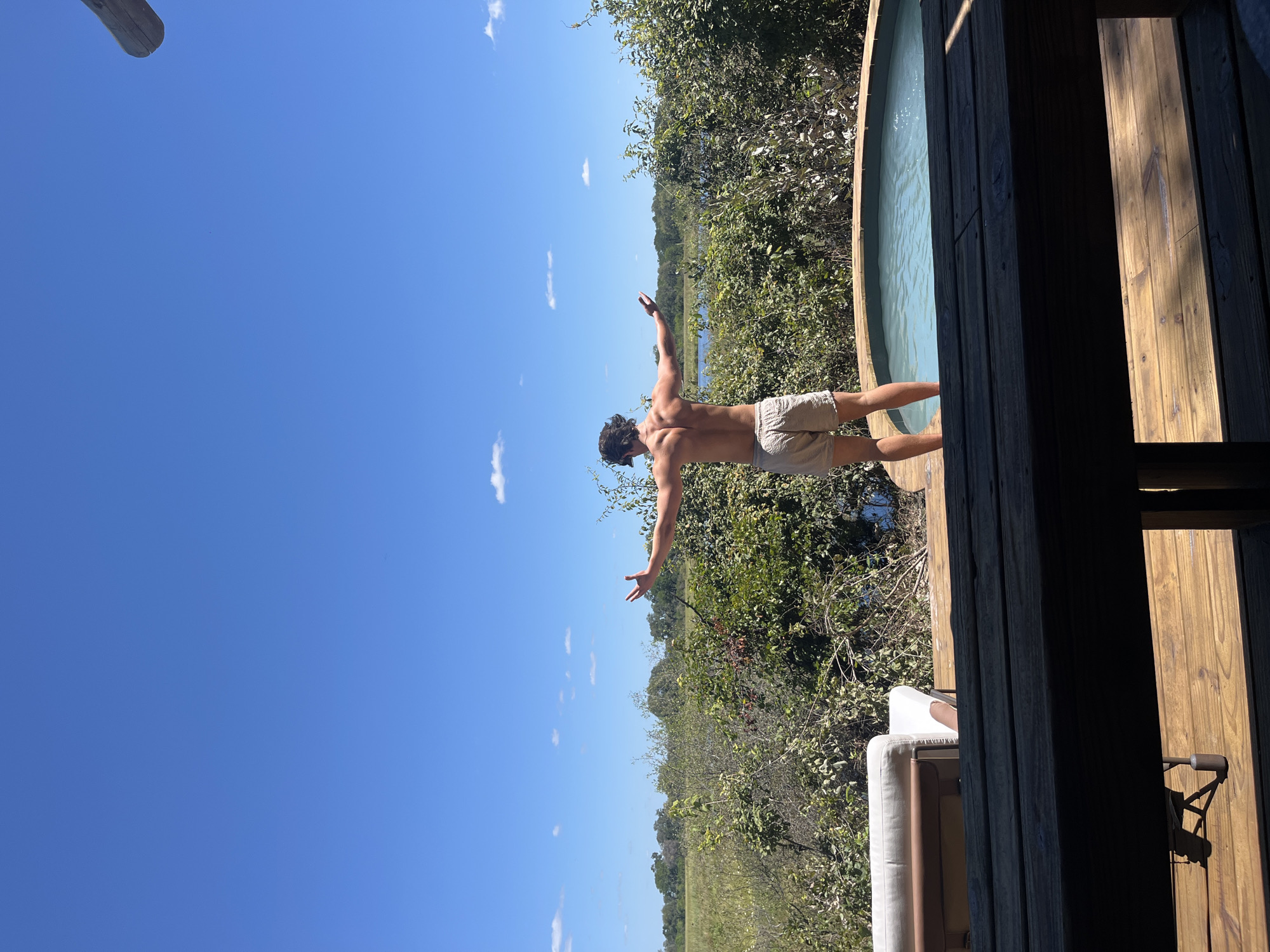 Man stands arms outstretched on deck in Khwai, Botswana