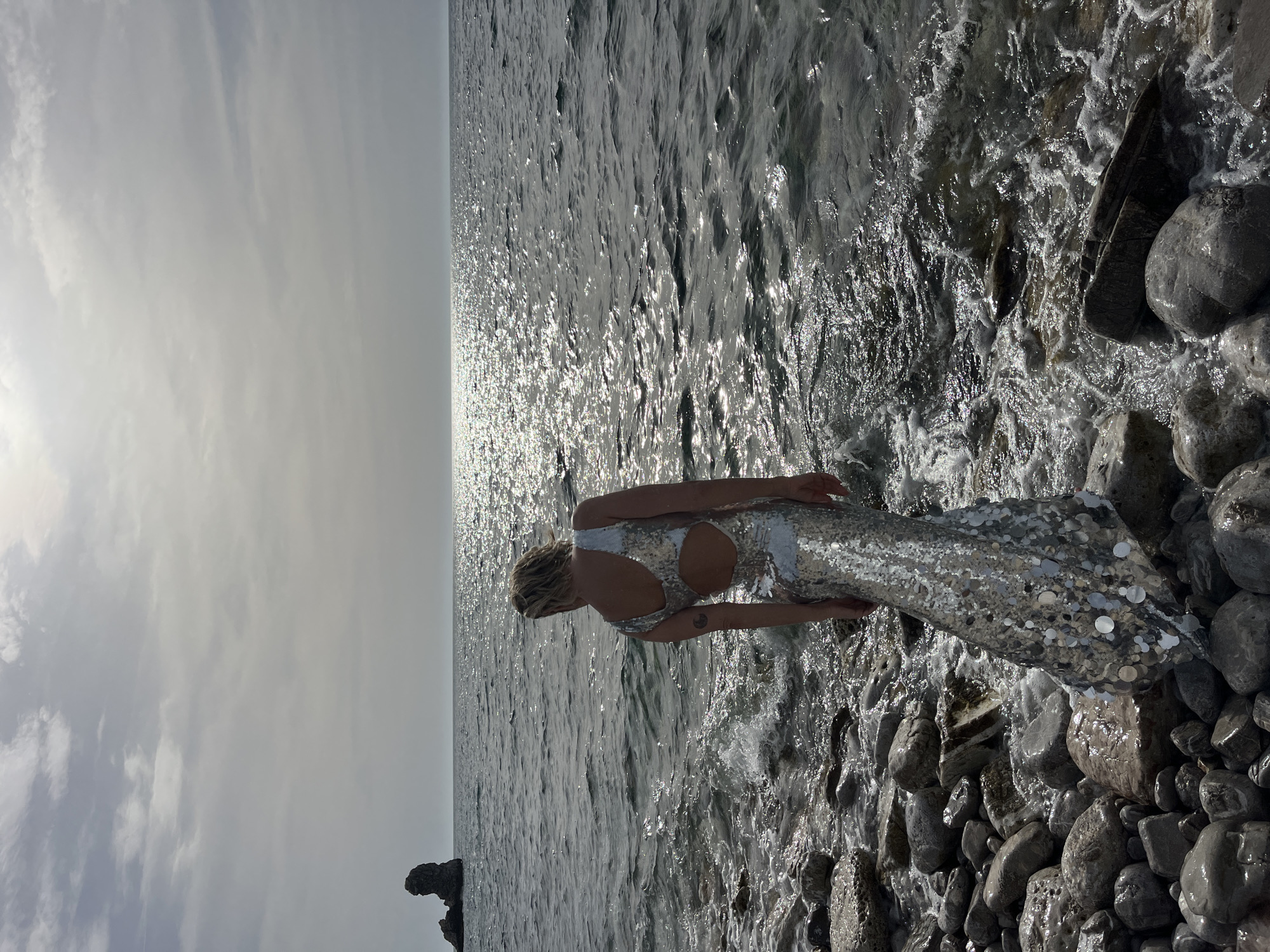 Woman contemplates sea from rocky Montenegro beach