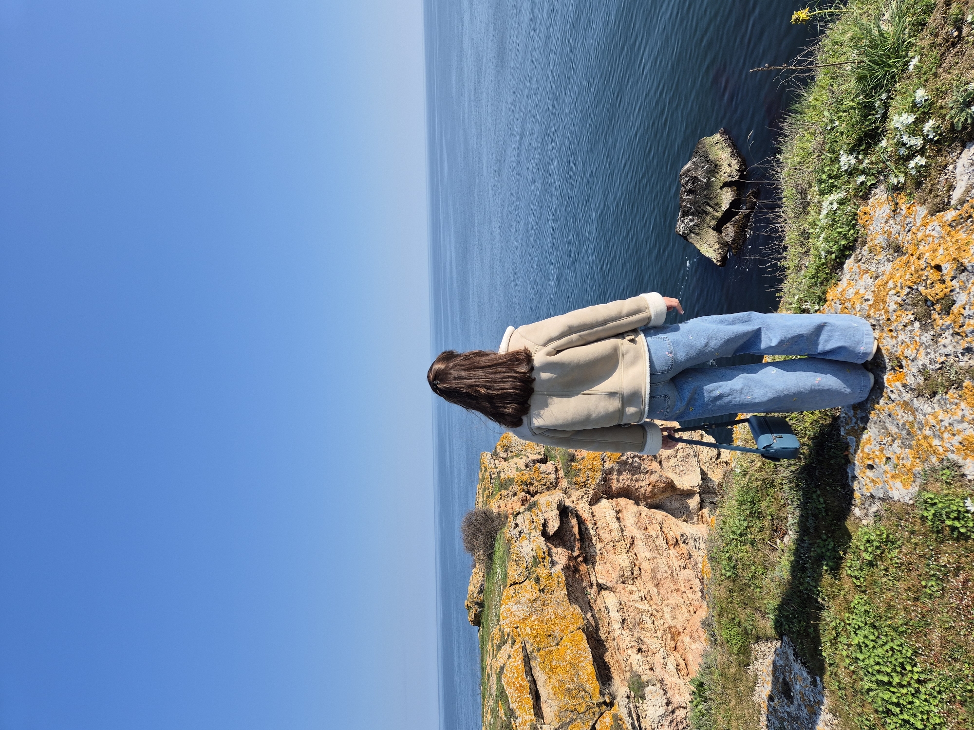 Woman photographs spring coastal scenery at Bulgarian Black Sea cliffs
