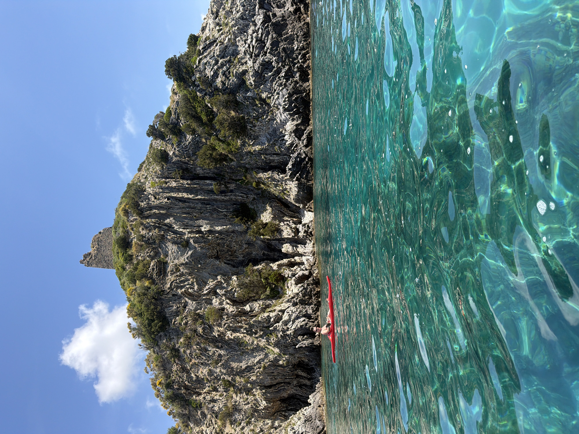 Kayaker paddles near Ascea cliffs in turquoise Mediterranean waters