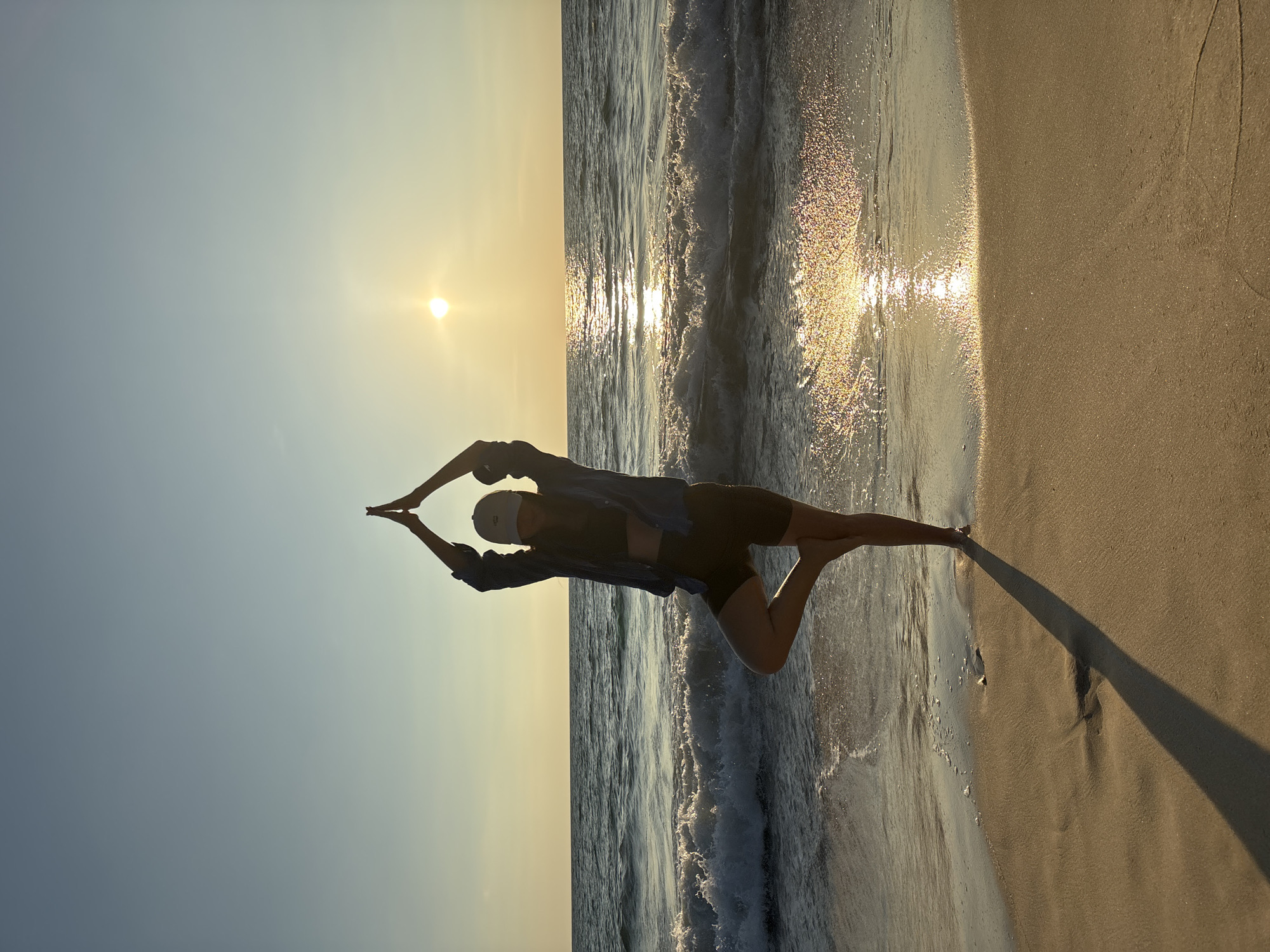 Person performs stretching pose on Choeng Thale beach