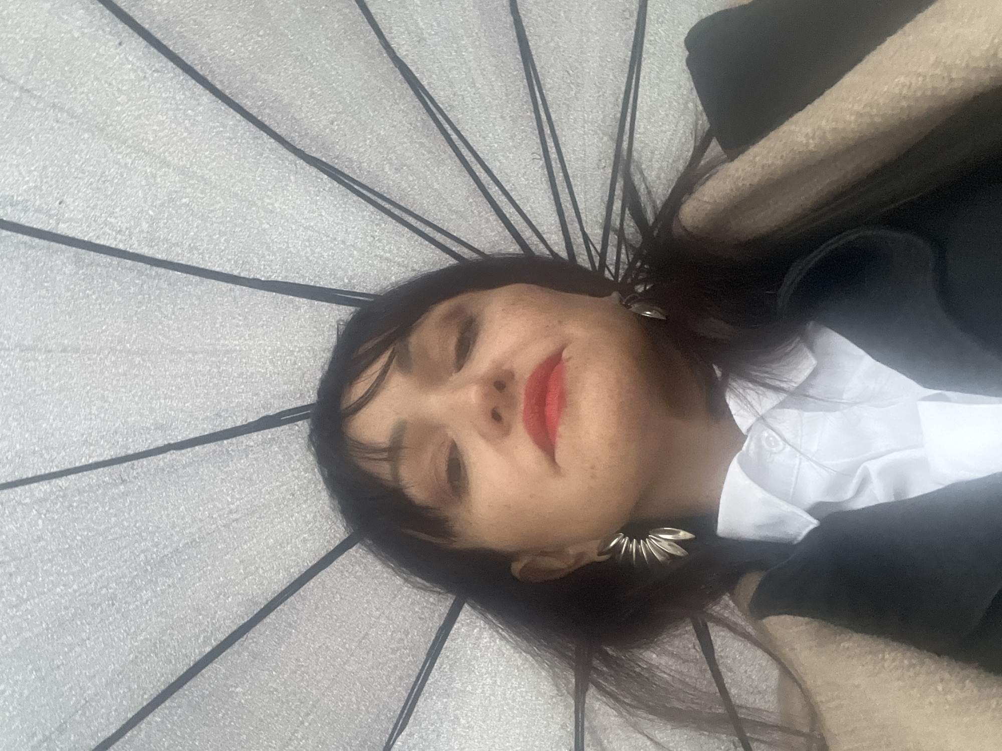 Woman shelters under umbrella during rainy afternoon in Perm