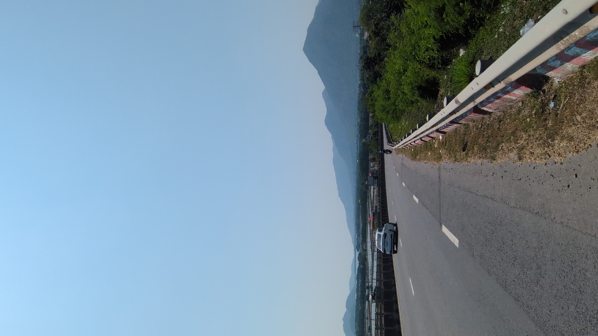 Vehicle travels Vietnamese road amid mountainous water landscape