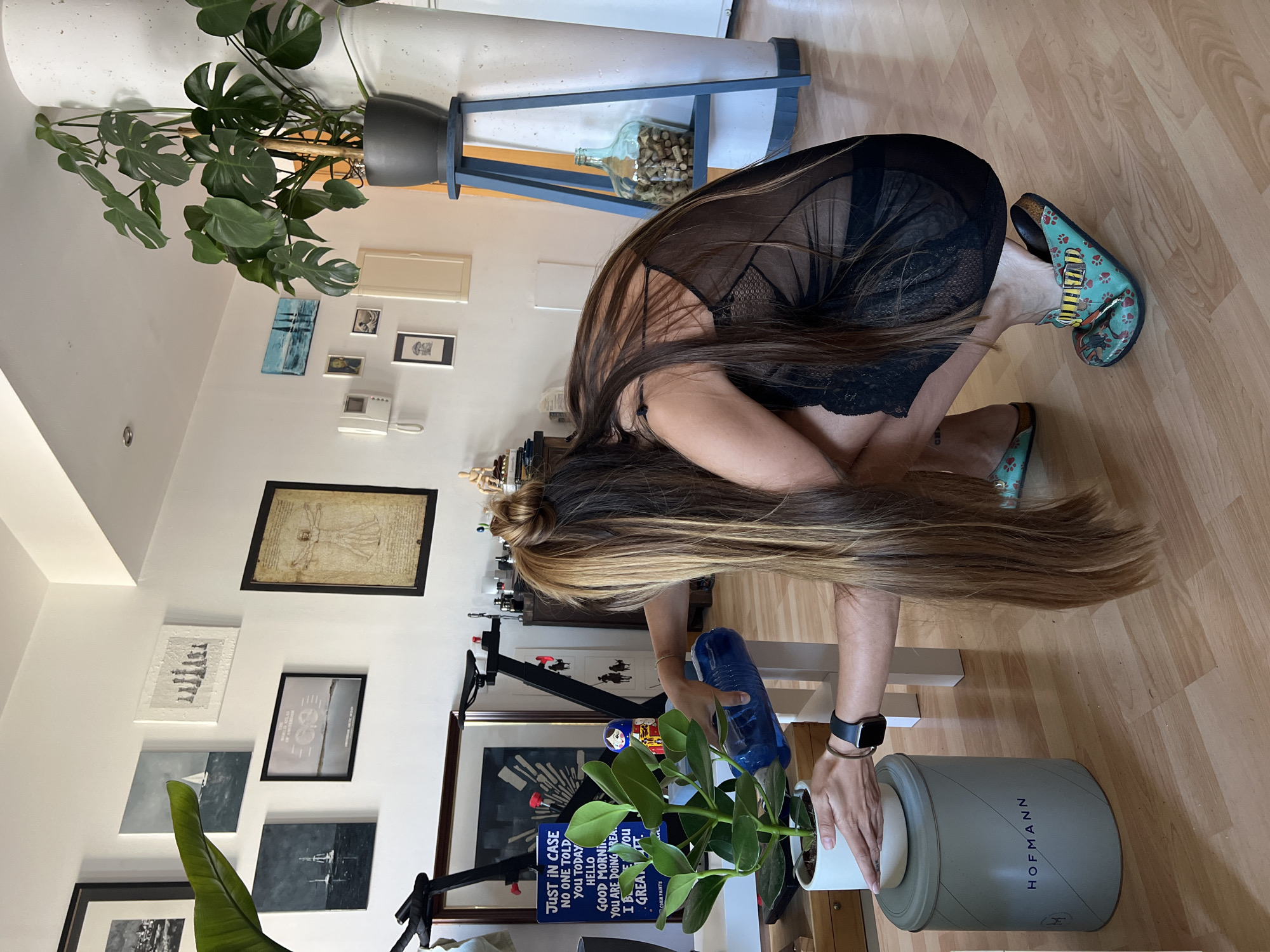 Woman waters indoor plant in Spanish home Monday morning