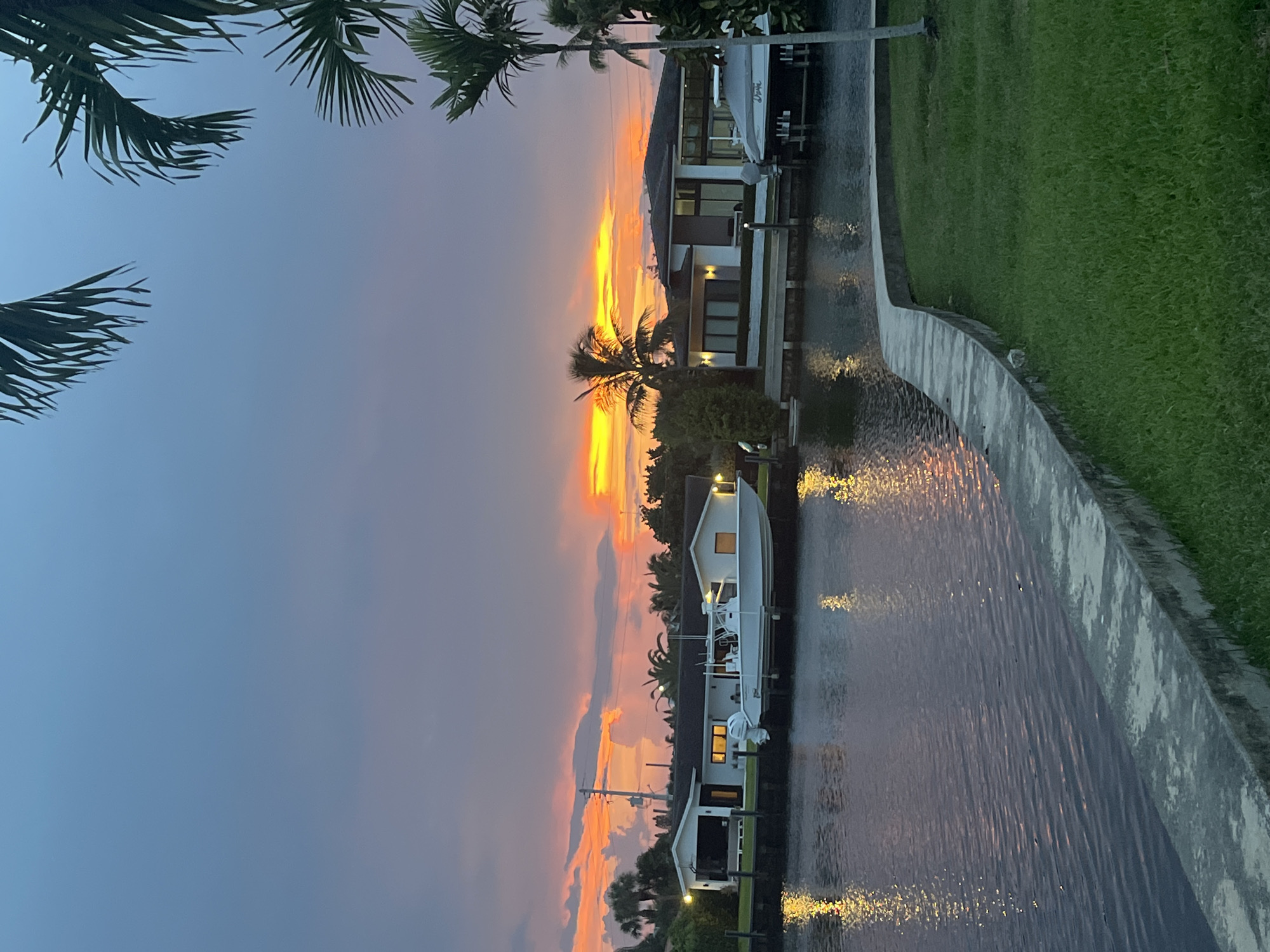 Residential canal glows under a vivid sunset sky