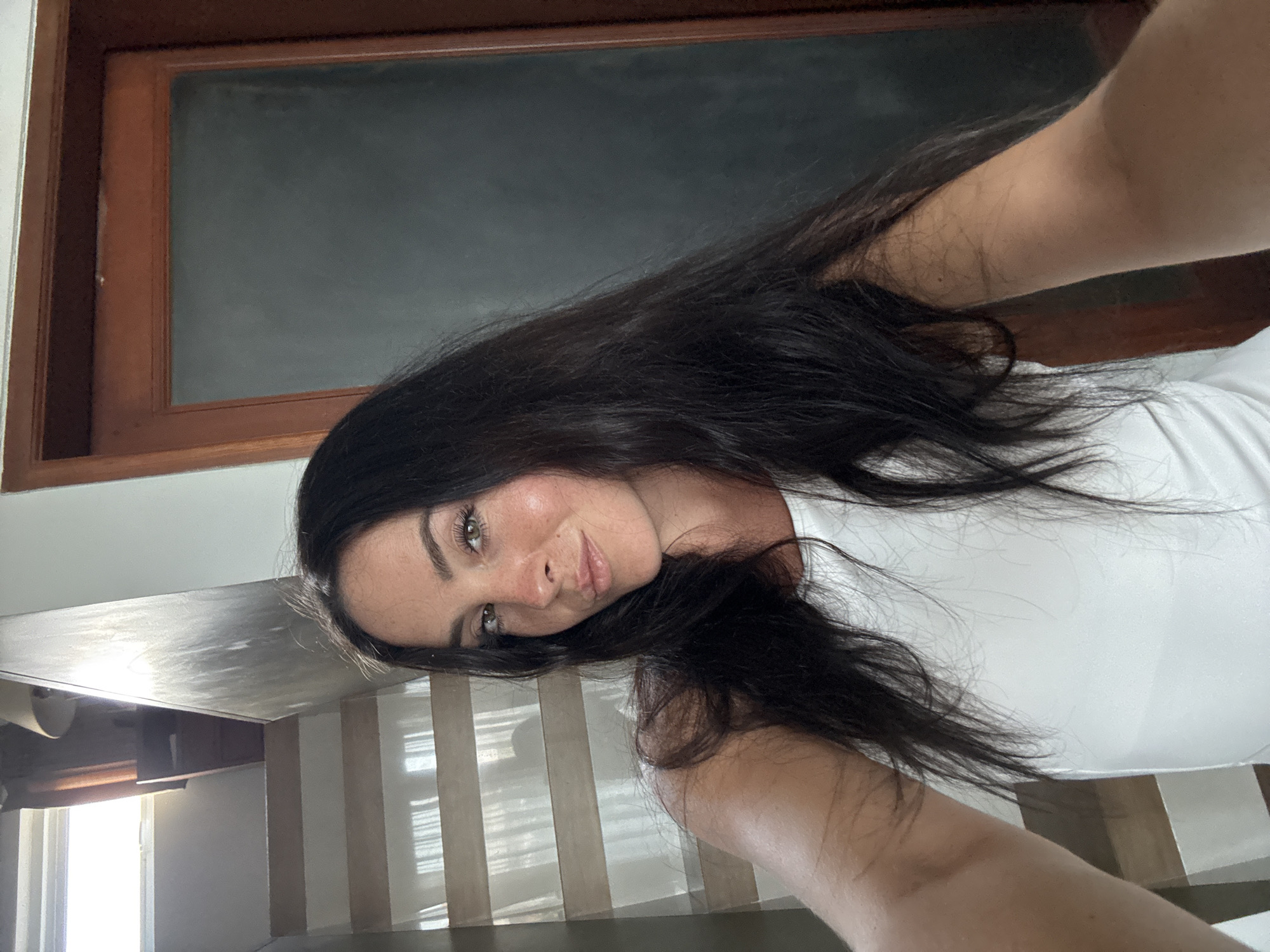 Mirror and direct selfies in a North Kuta room, white outfit.