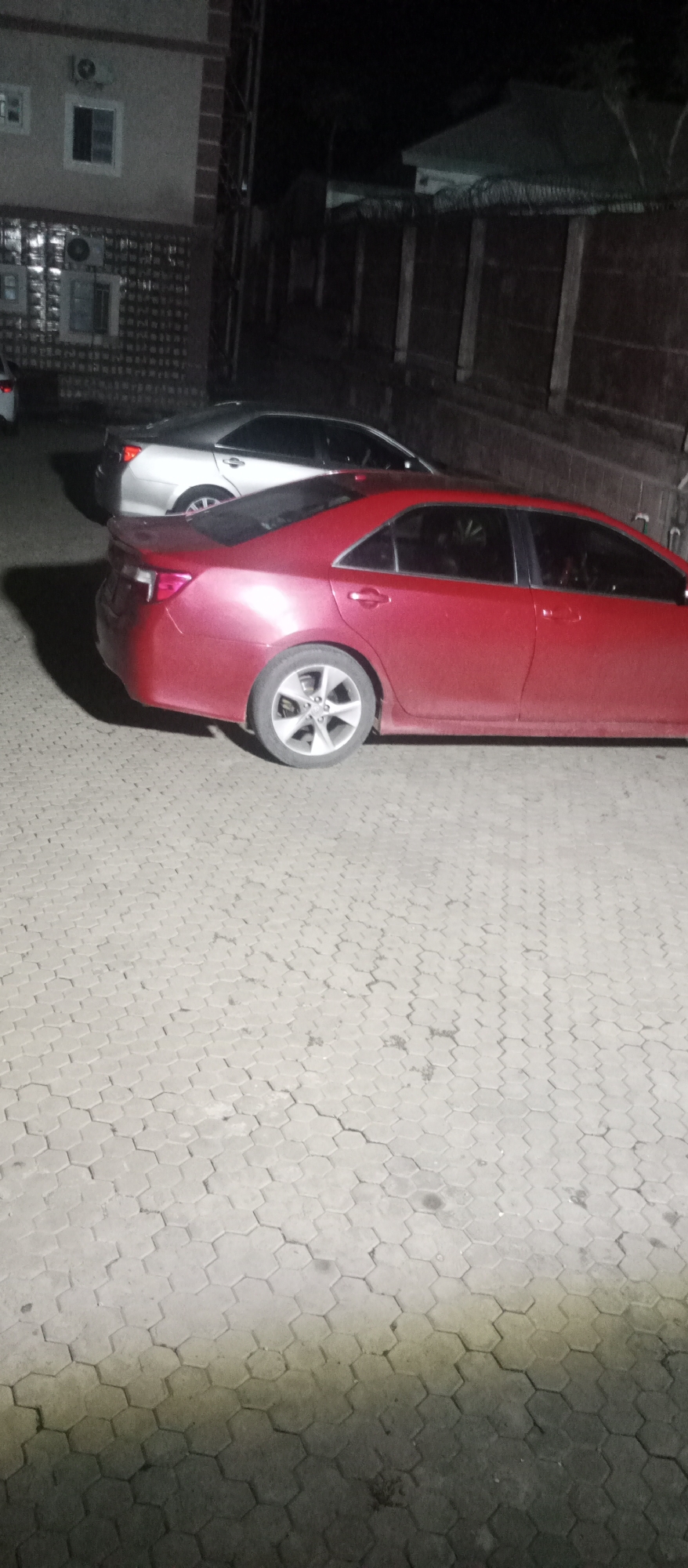 Nighttime exploration of residential compound with parked cars and courtyards