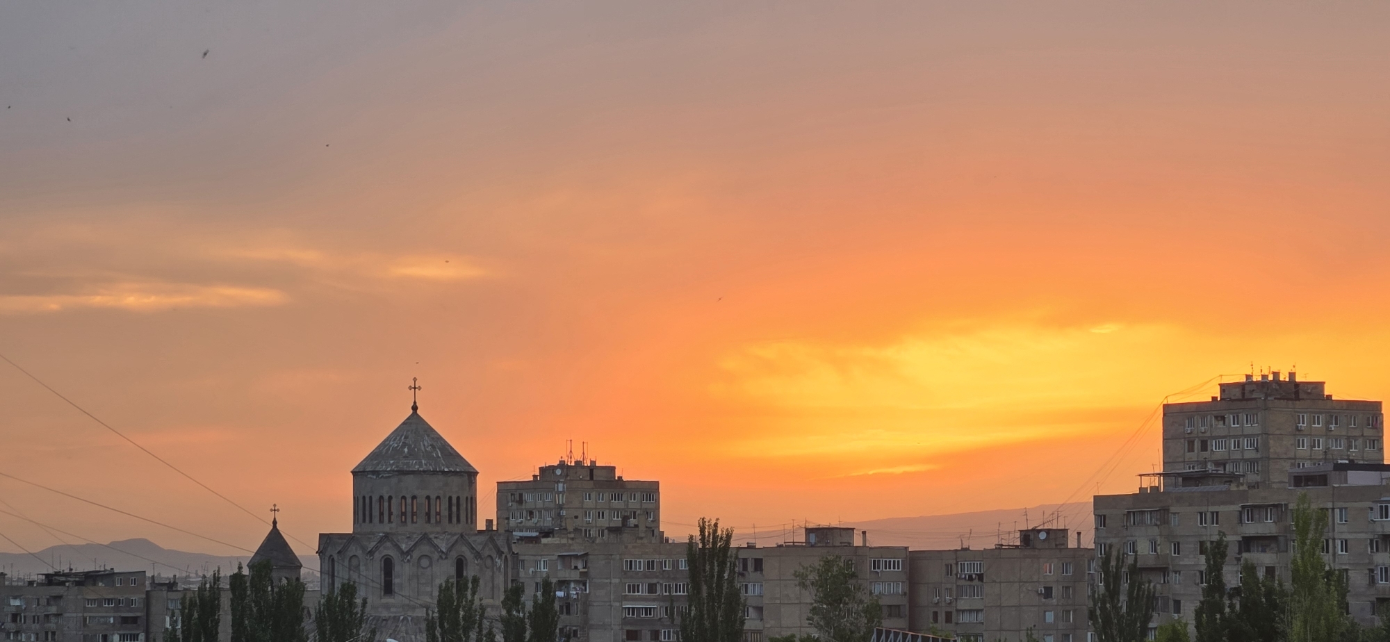 Sunset illuminates Yerevan skyline with church and Soviet buildings