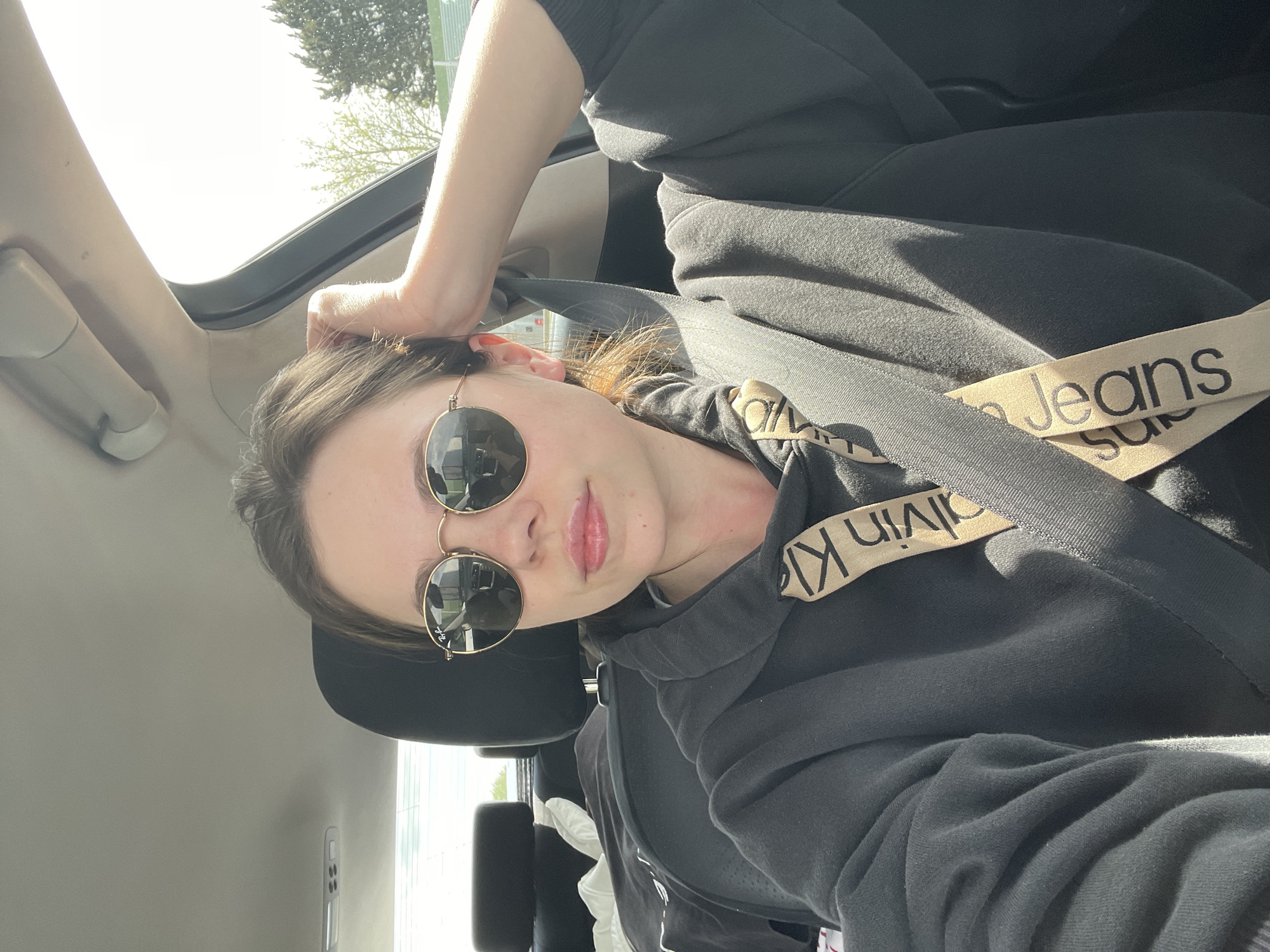 Woman in sunglasses photographed in car with open sunroof