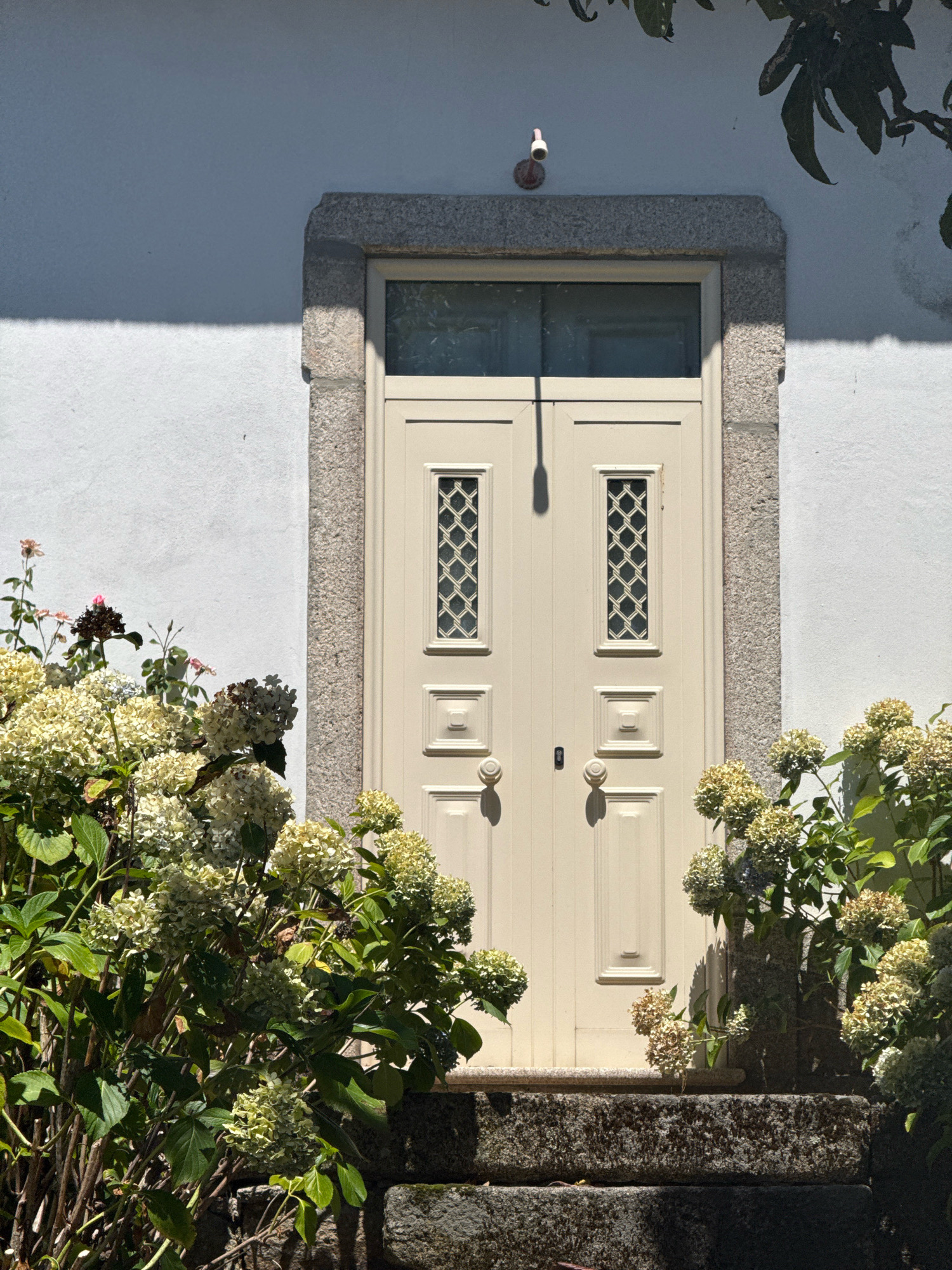 Stone-arched doorway with latticed double doors in Alijó