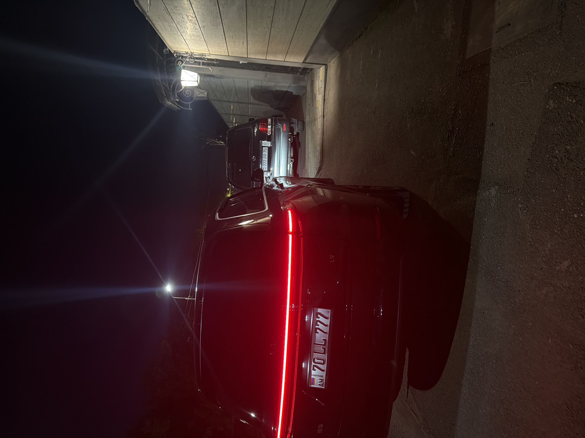 Vehicles parked under carport, SUV tail lights on
