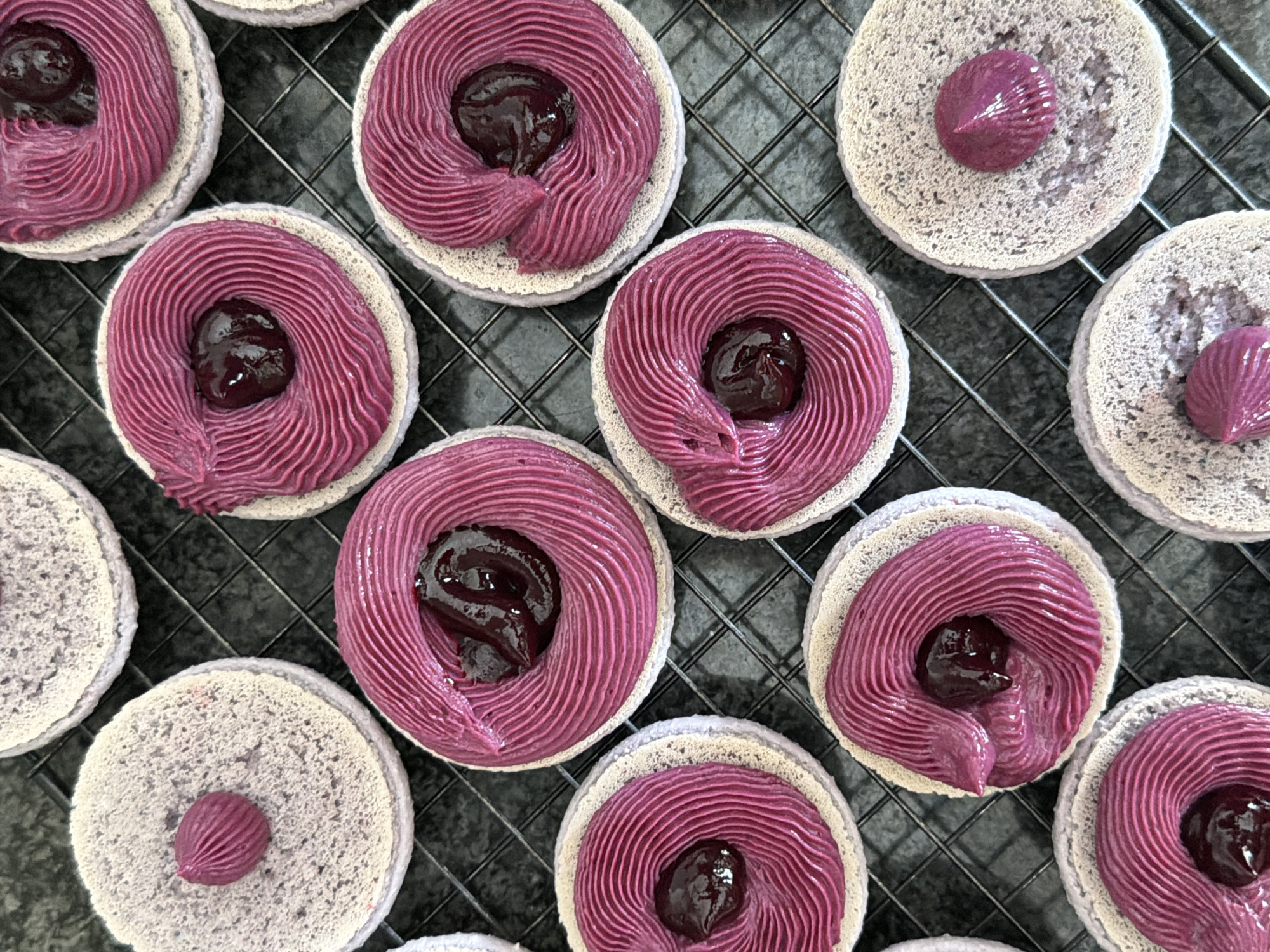 Baker decorates lavender macarons with purple frosting in Tel Aviv