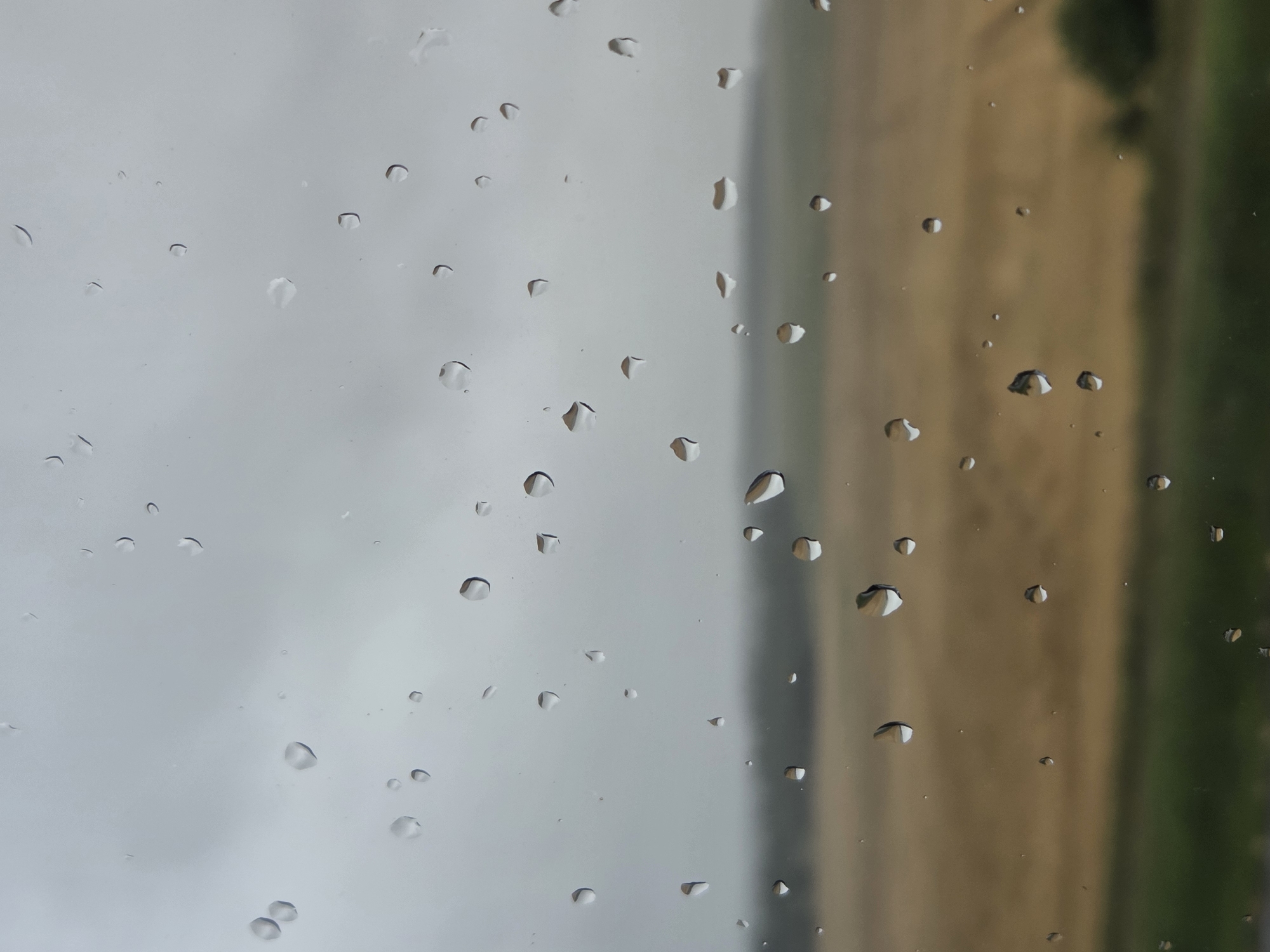 Rain on the glass, fields and parking lot beyond