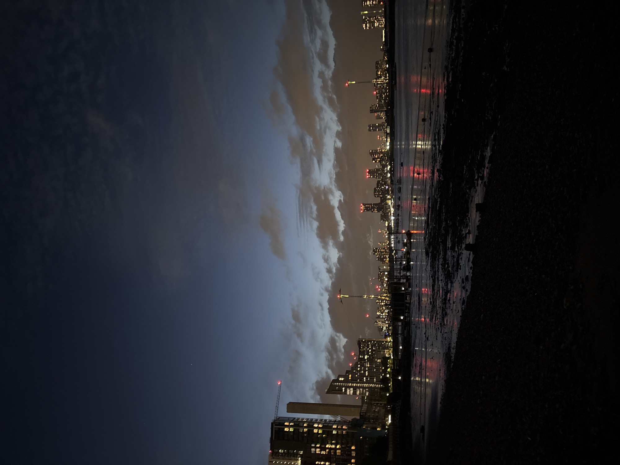 London waterfront captured at night with lit buildings, cranes