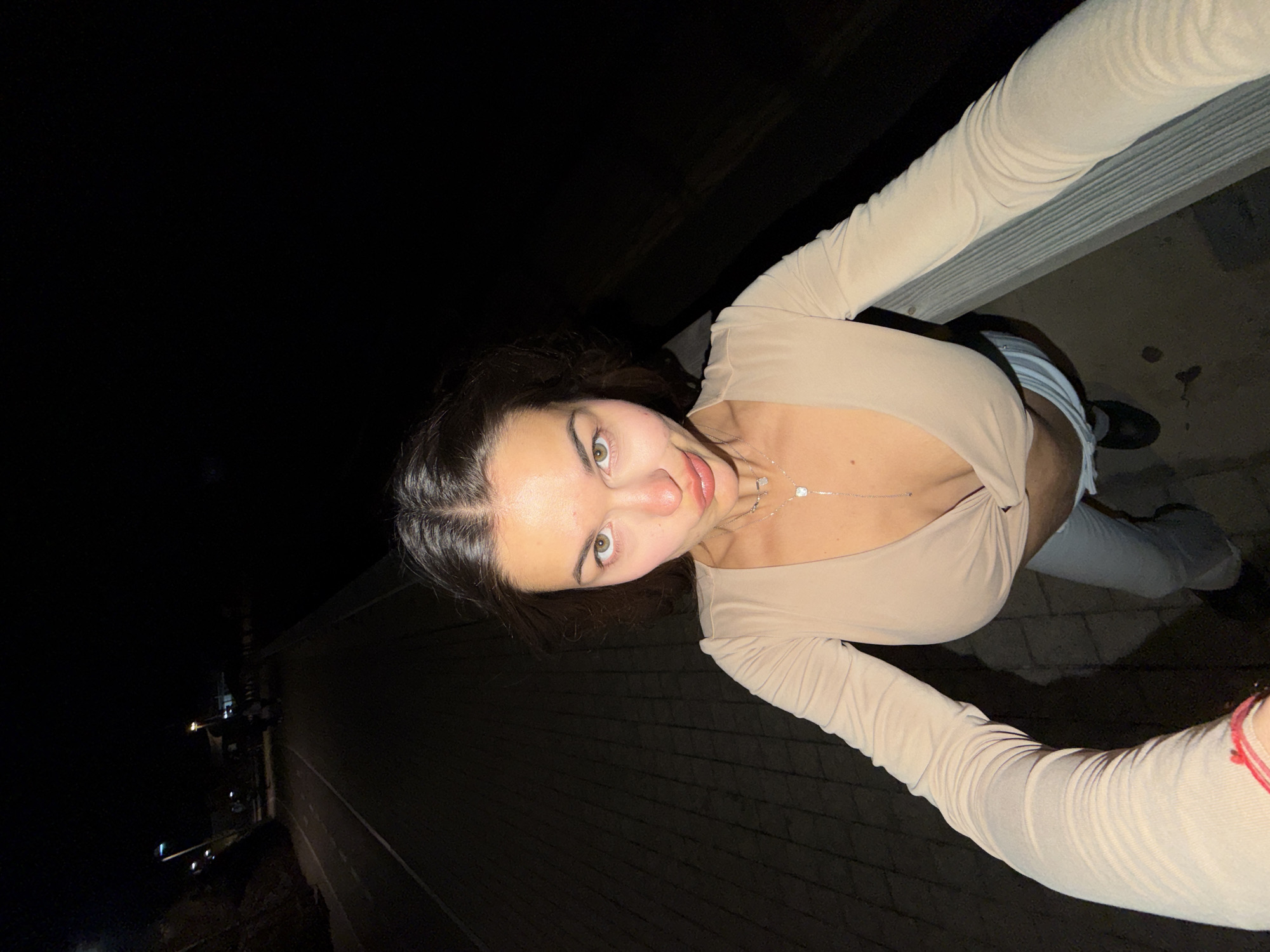 Woman poses for nighttime photos on waterfront promenade