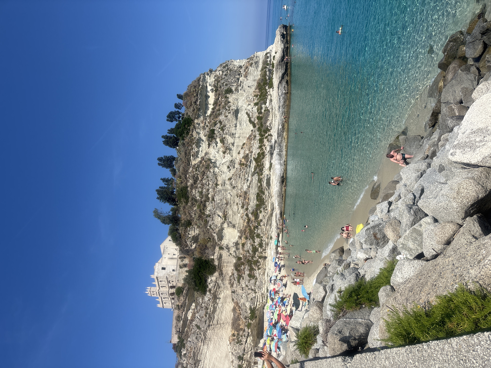 Busy summer morning at Tropea beach beneath the clifftop sanctuary