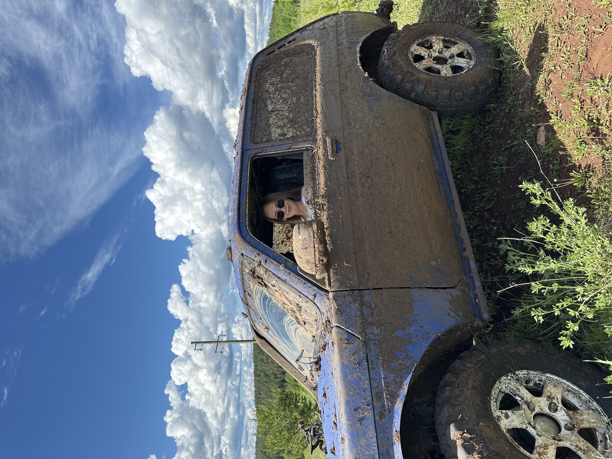 Off-road enthusiasts gather with muddy vehicles in Russian countryside