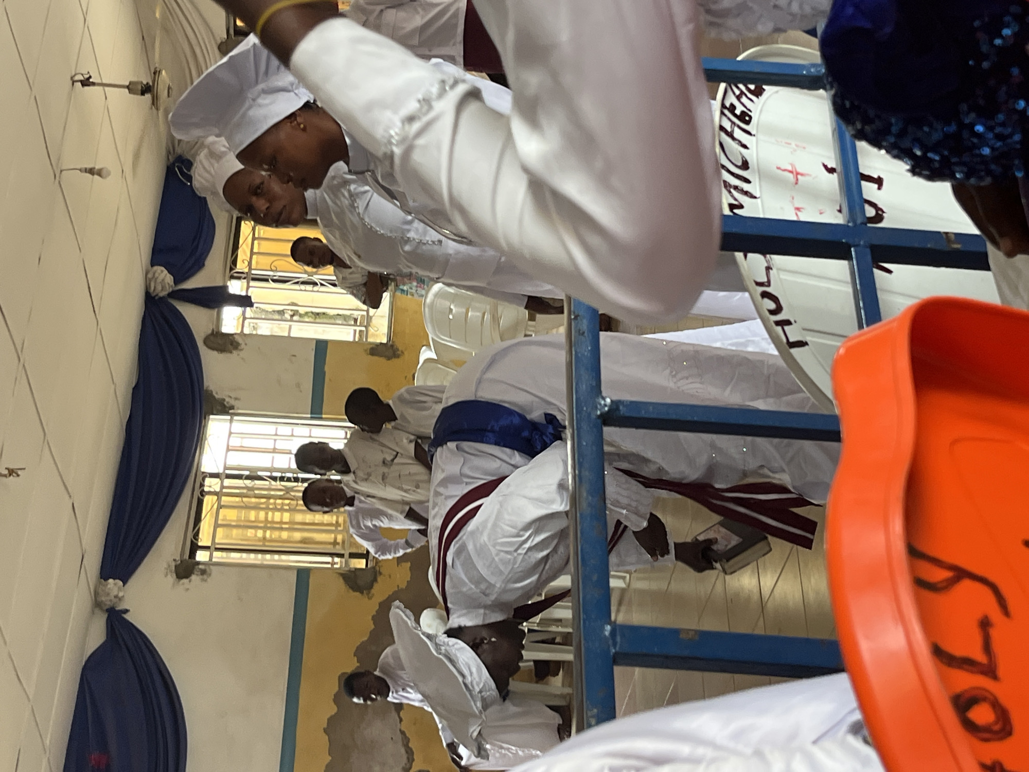 Religious service in community hall with white-robed congregation