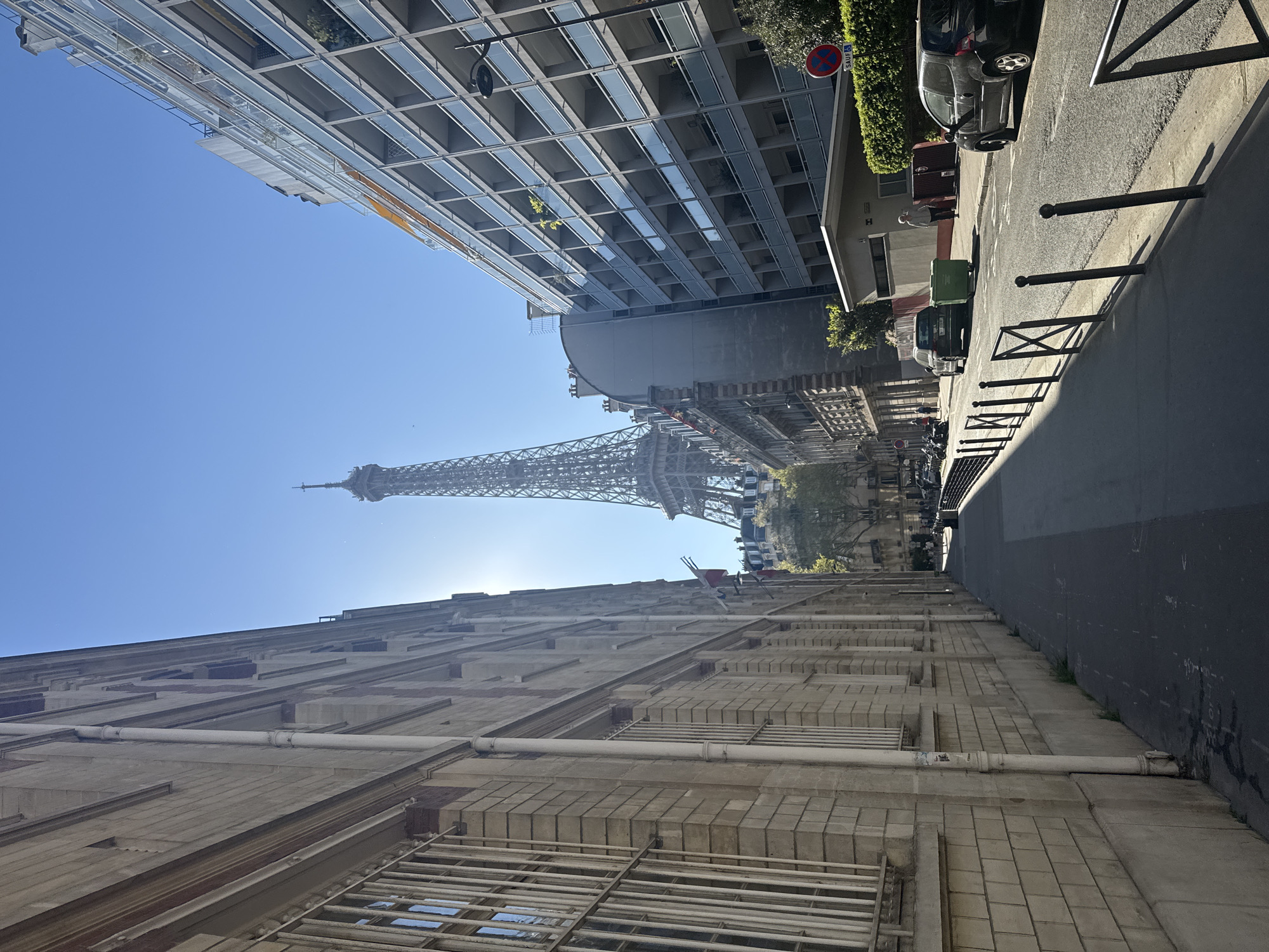 Tourist photographs Eiffel Tower from below on sunny afternoon