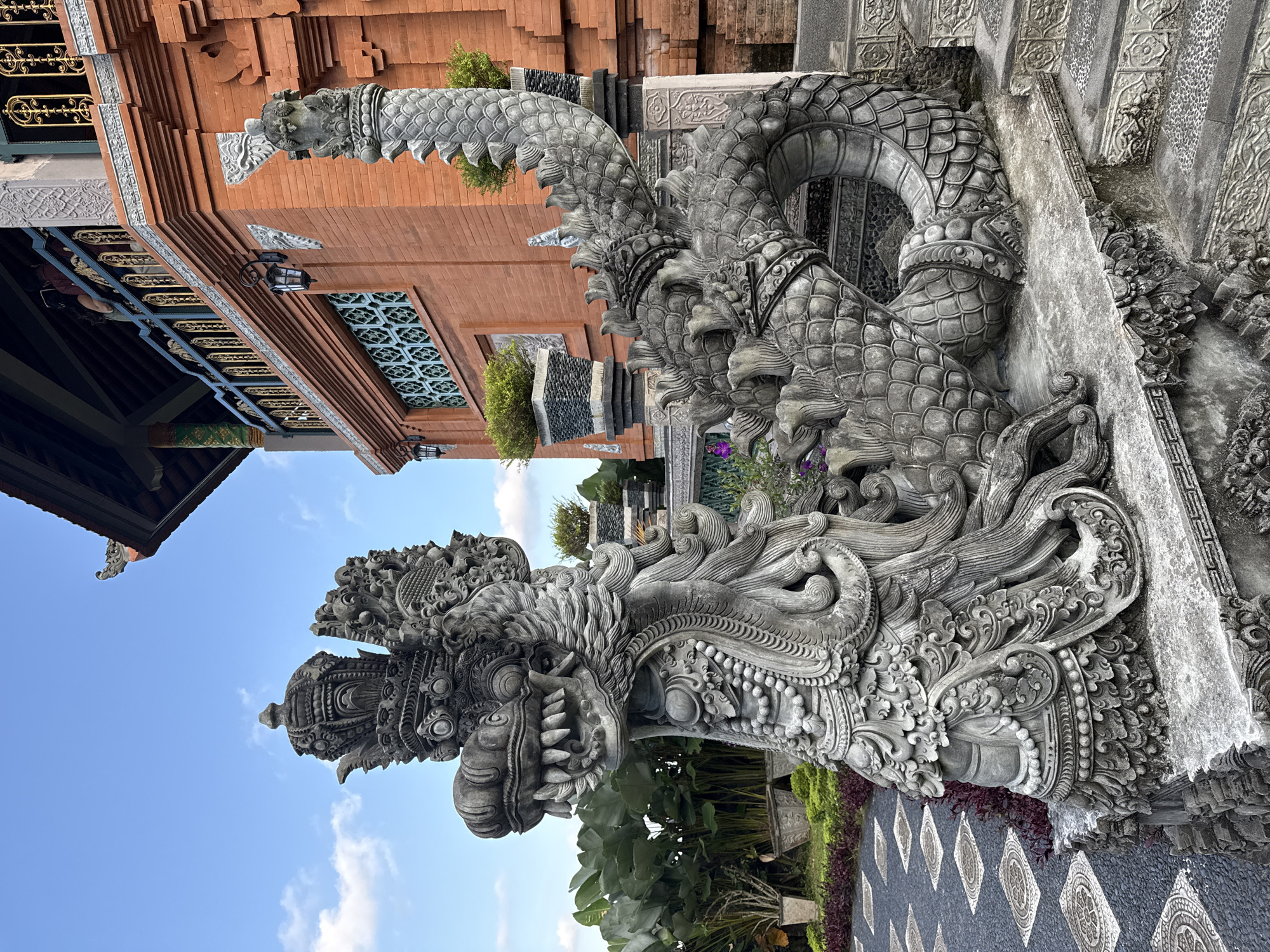 Tourist photographs document Tirtagangga Water Palace stone dragons, Bali