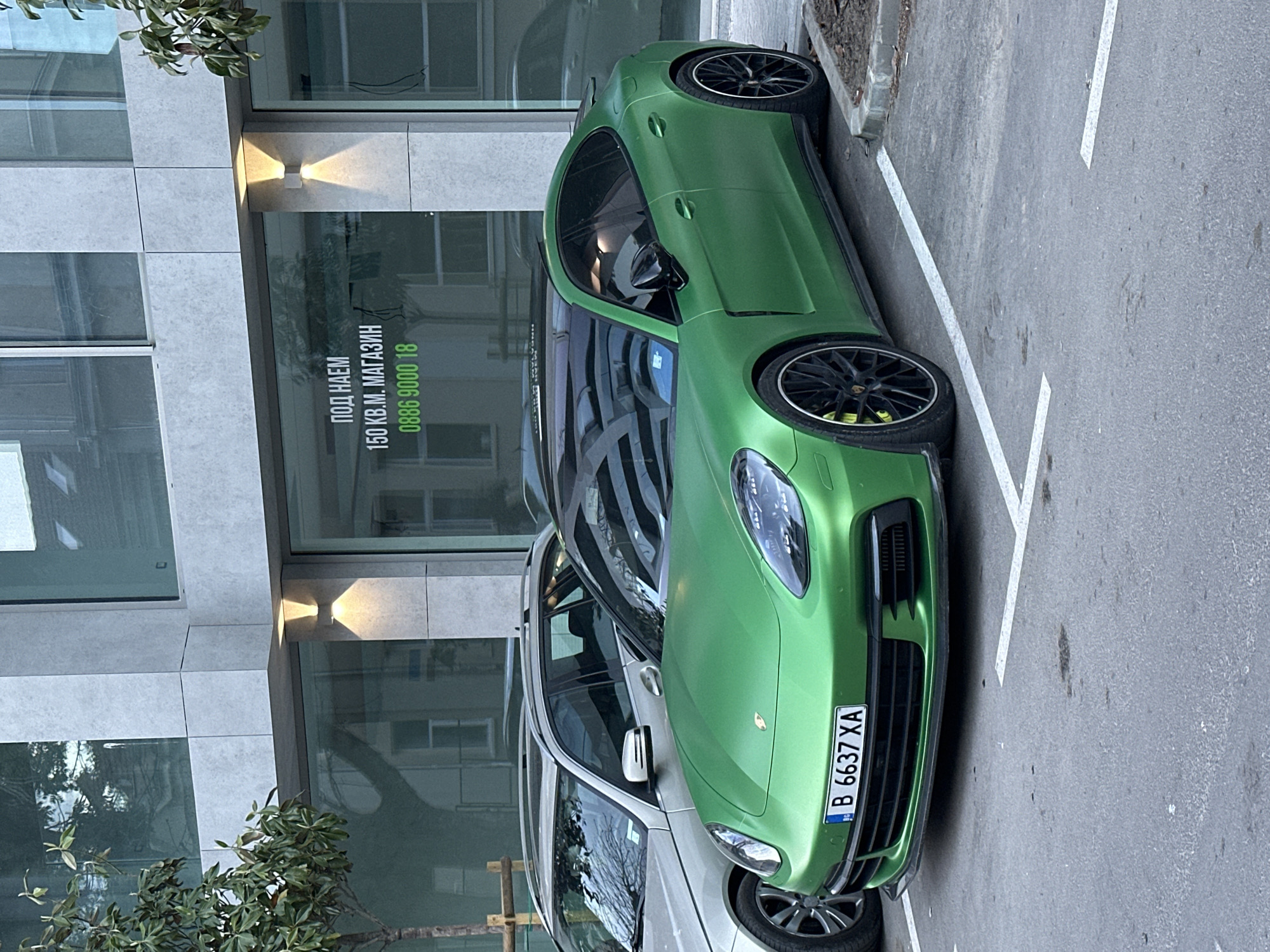 Green Porsche parked outside modern building in Varna, Bulgaria
