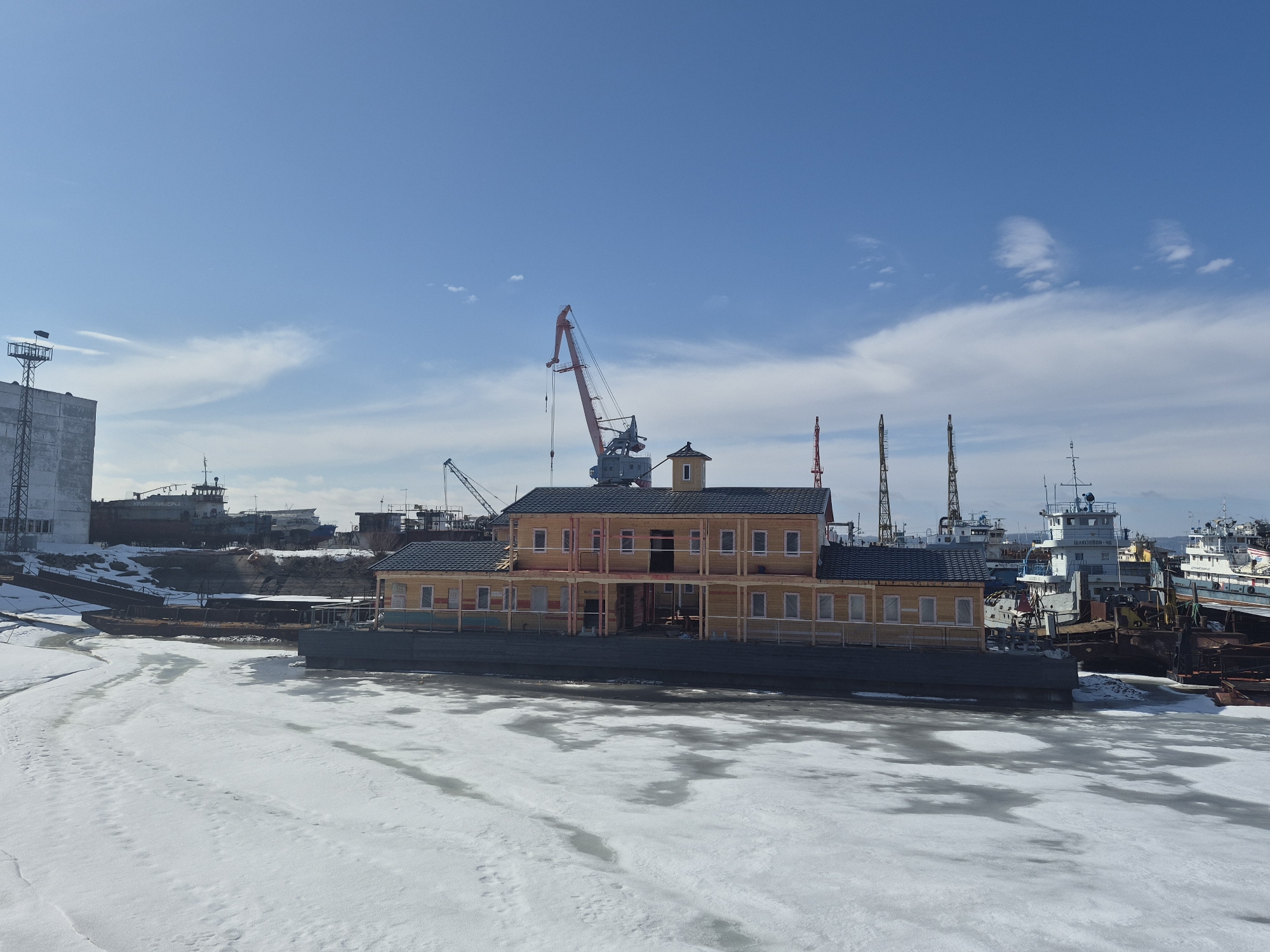 Yellow building transported by barge through partially frozen waters