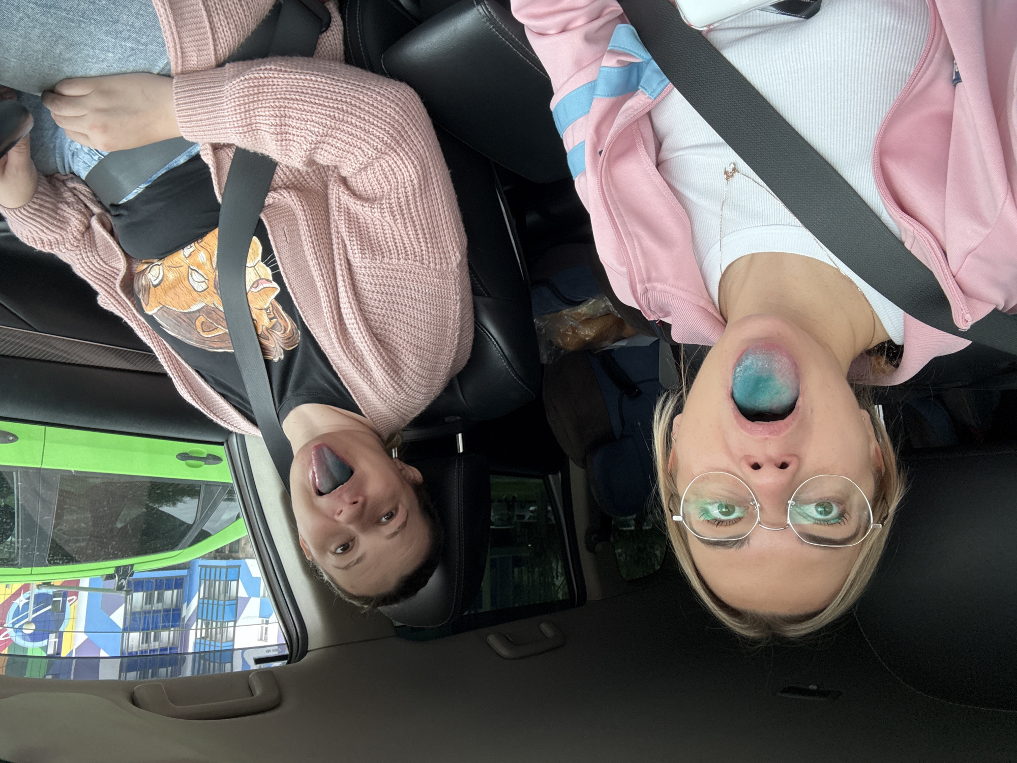Two women show blue-stained tongues while seated in Krasnoyarsk car