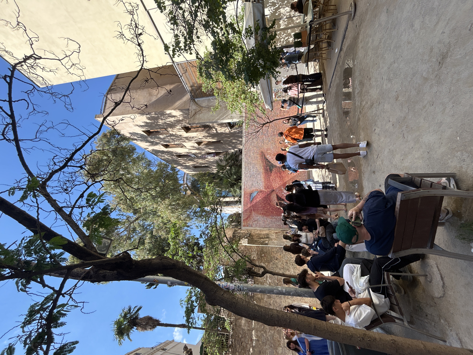 Crowds queue, photograph face mural in Barcelona courtyard