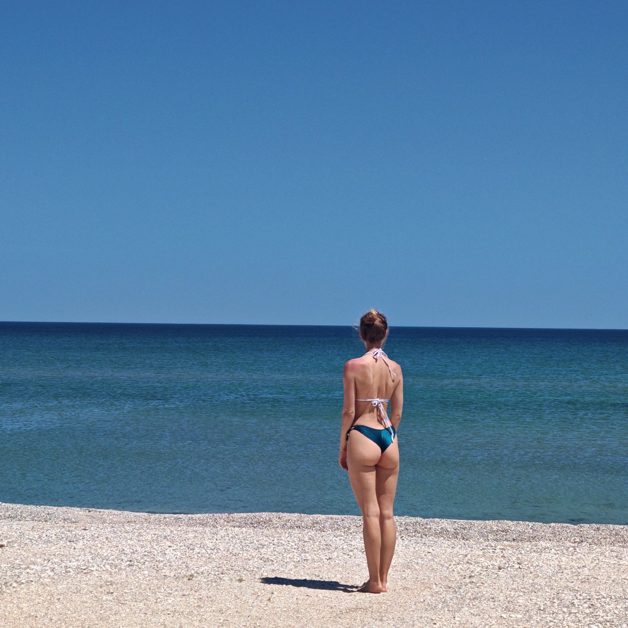 Beachgoers enjoy calm morning on shell-covered beach