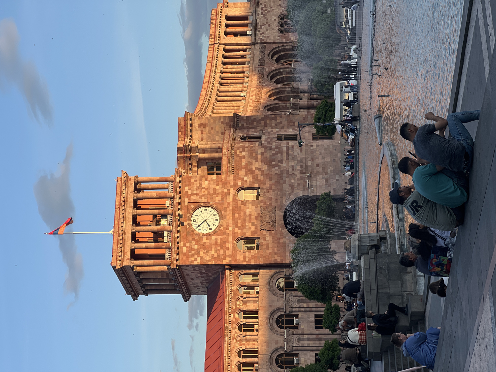 Clock tower with Armenian flag observed near public fountain