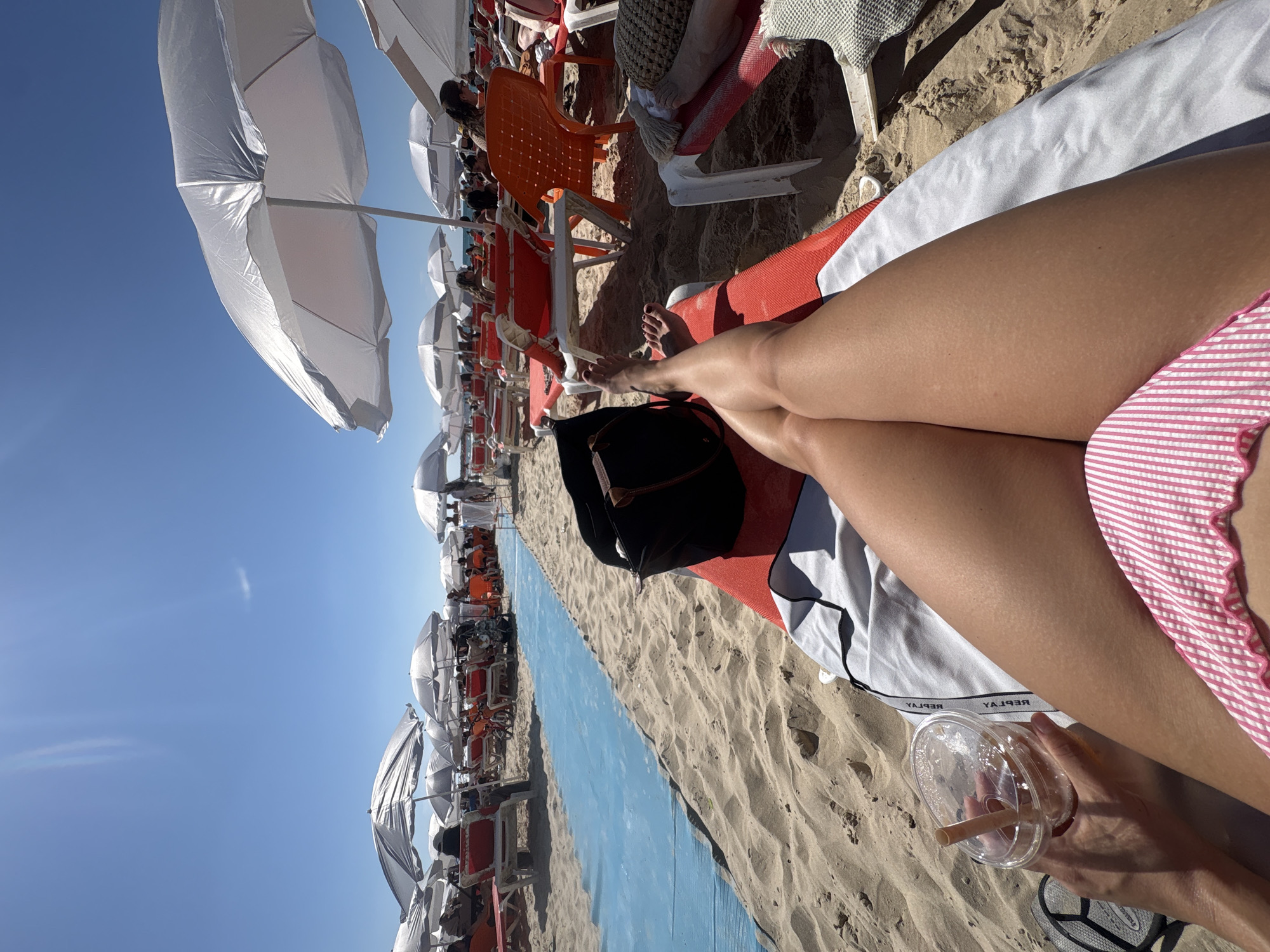 Beachgoer enjoys drink while sunbathing in Tel Aviv