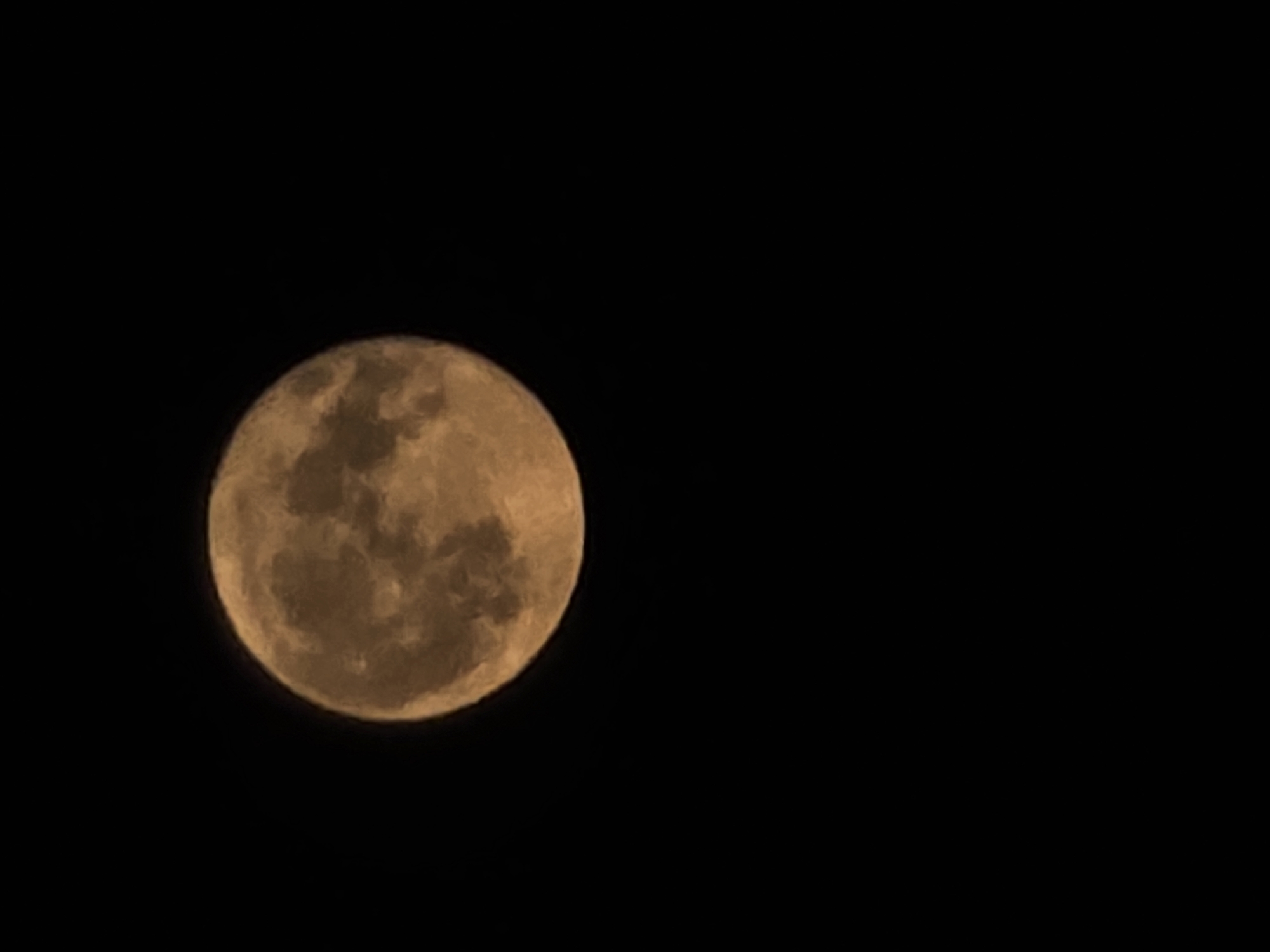 Full moon rising over a glowing city skyline at night