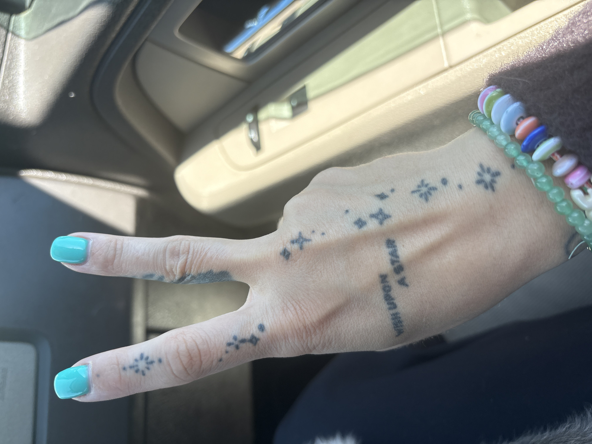 Person flashes peace sign with star tattoos in Long Beach car