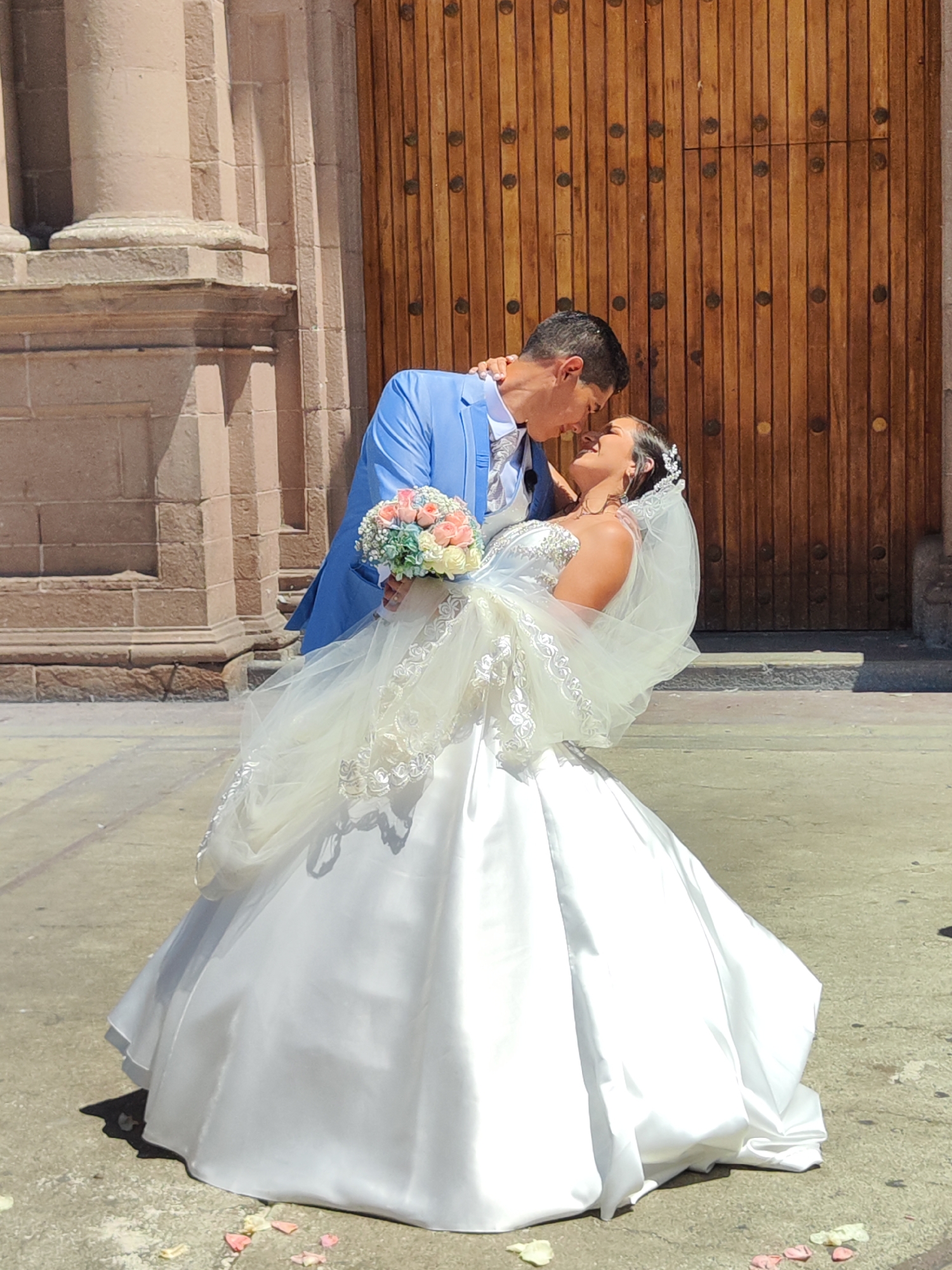 Newlywed couple embraces outside building in Tacna, Peru