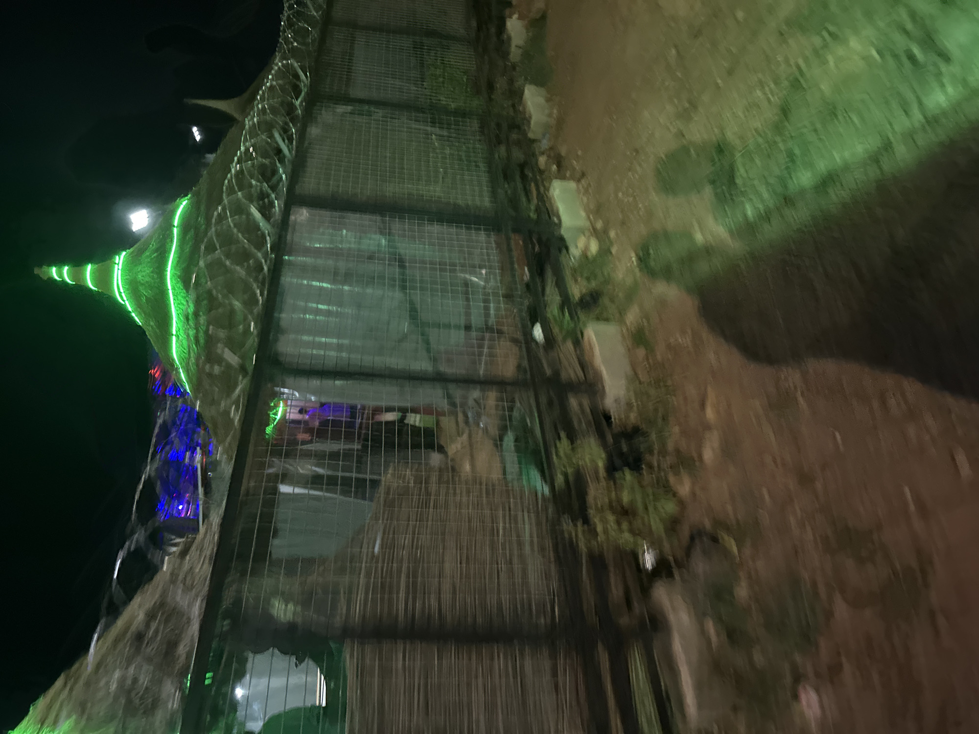 Illuminated tower structure observed behind fence in Jos, Nigeria