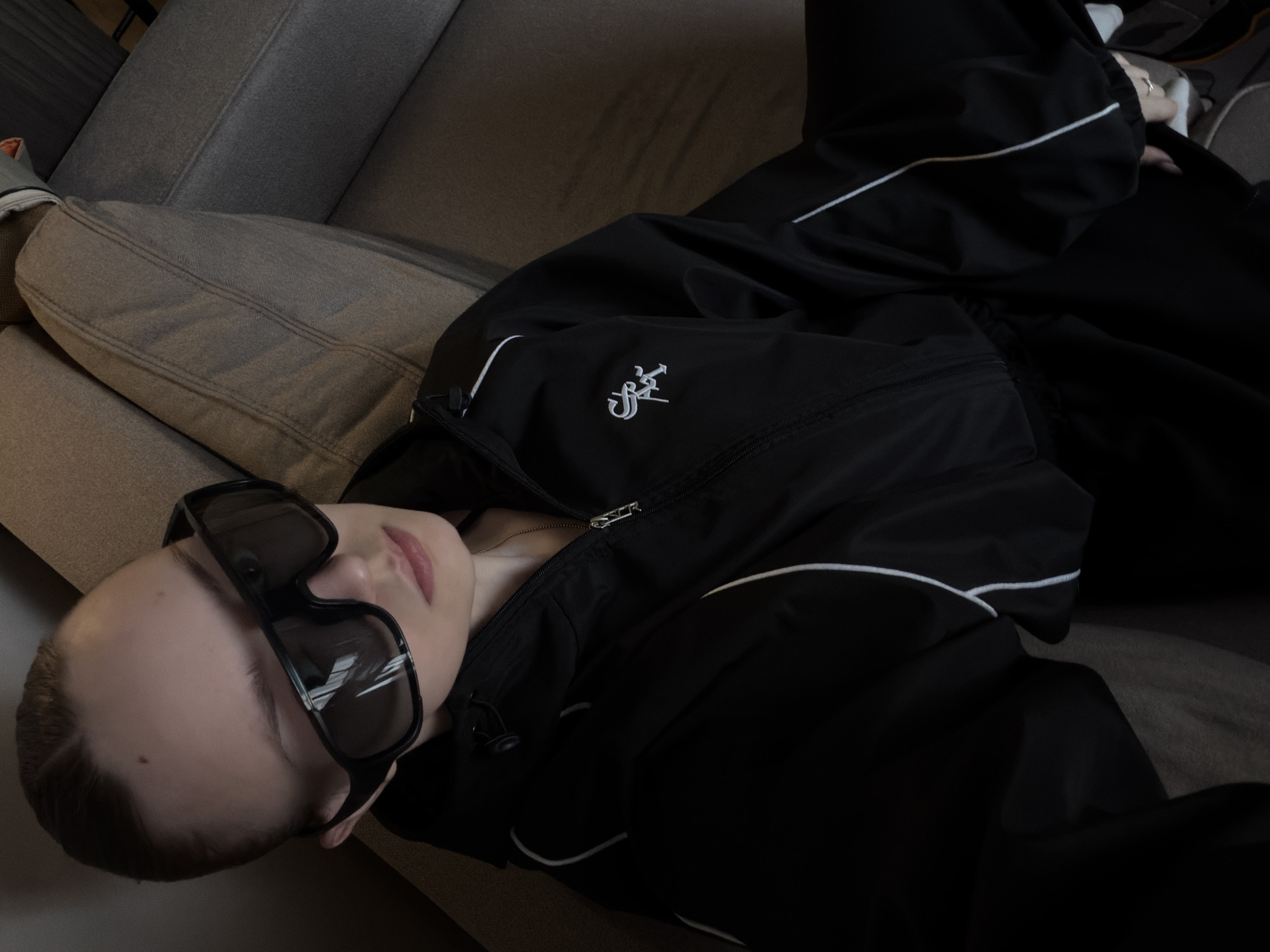 Person in black tracksuit rests on sofa in Moscow