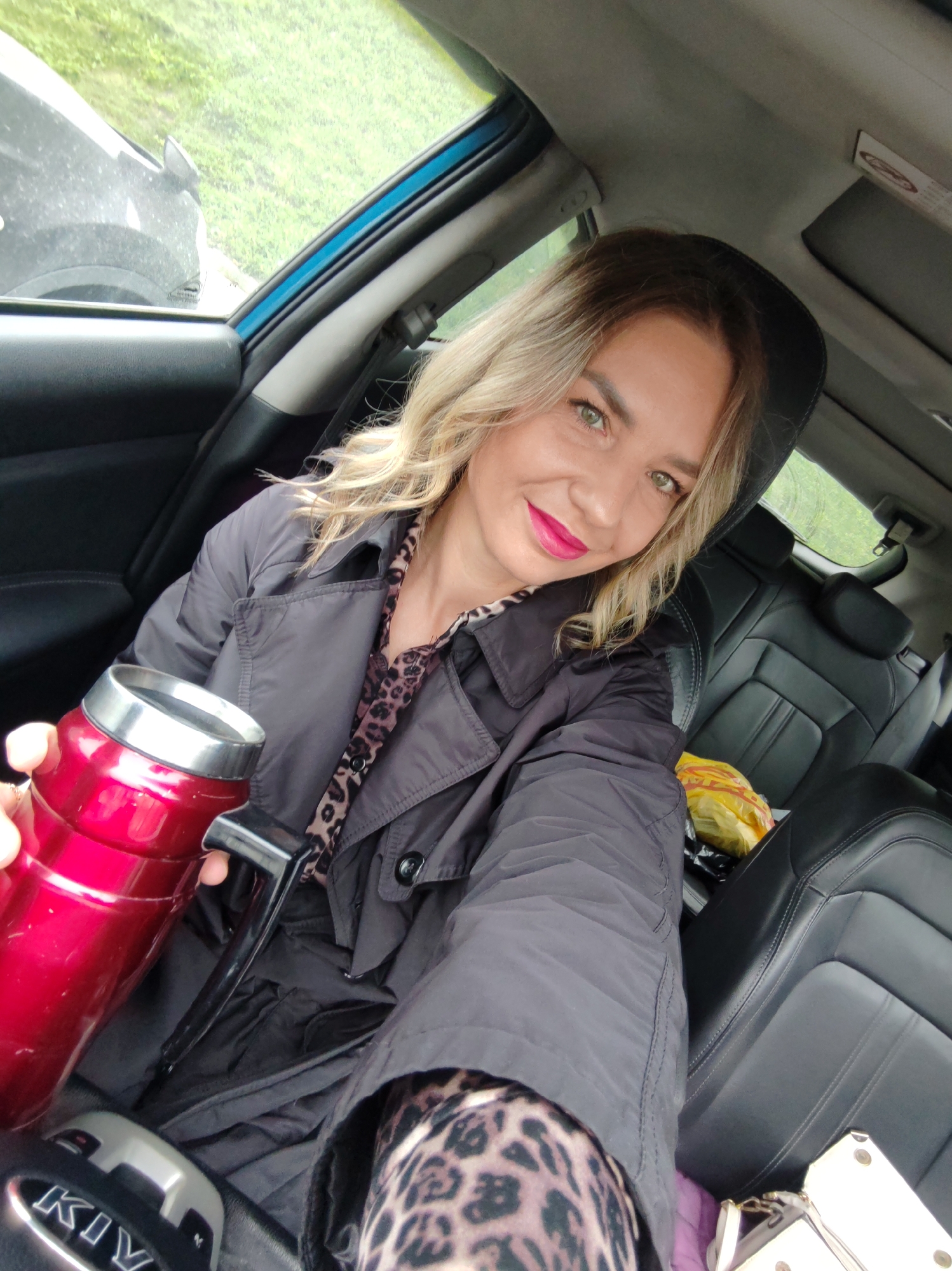 Woman takes selfies, applies makeup in car driver's seat