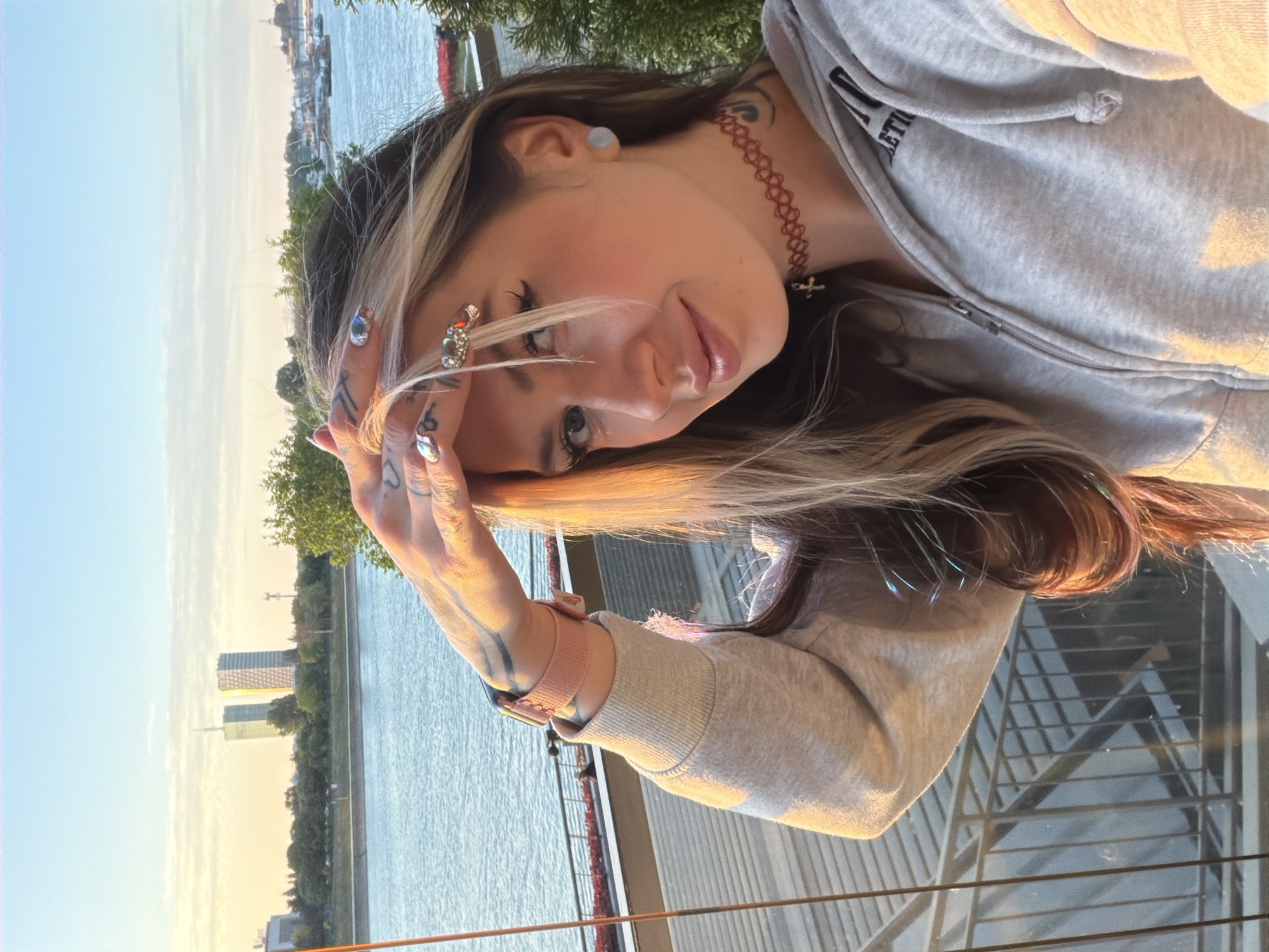Woman photographs herself at Belgrade riverfront overlook during golden hour