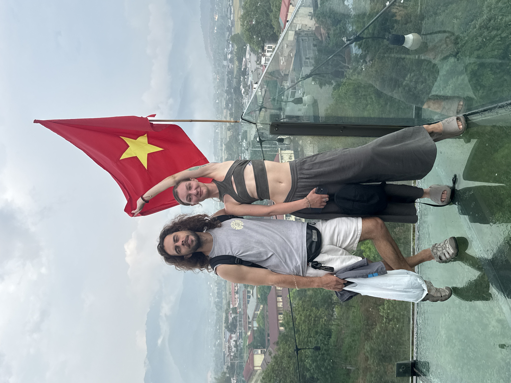 Tourists pose with Vietnamese flag on glass viewing platform