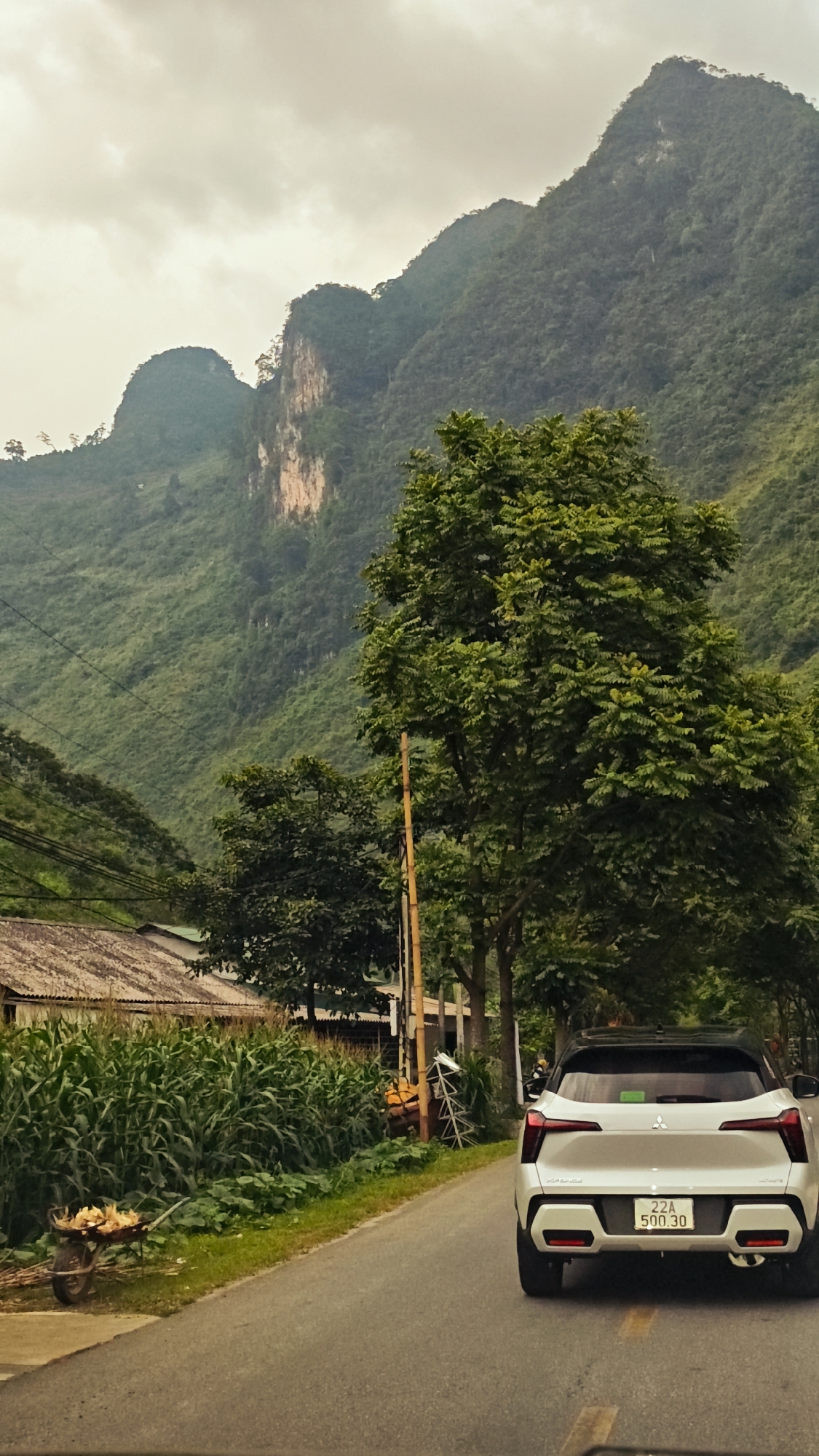 White Mitsubishi travels rural road in northern Vietnam commune