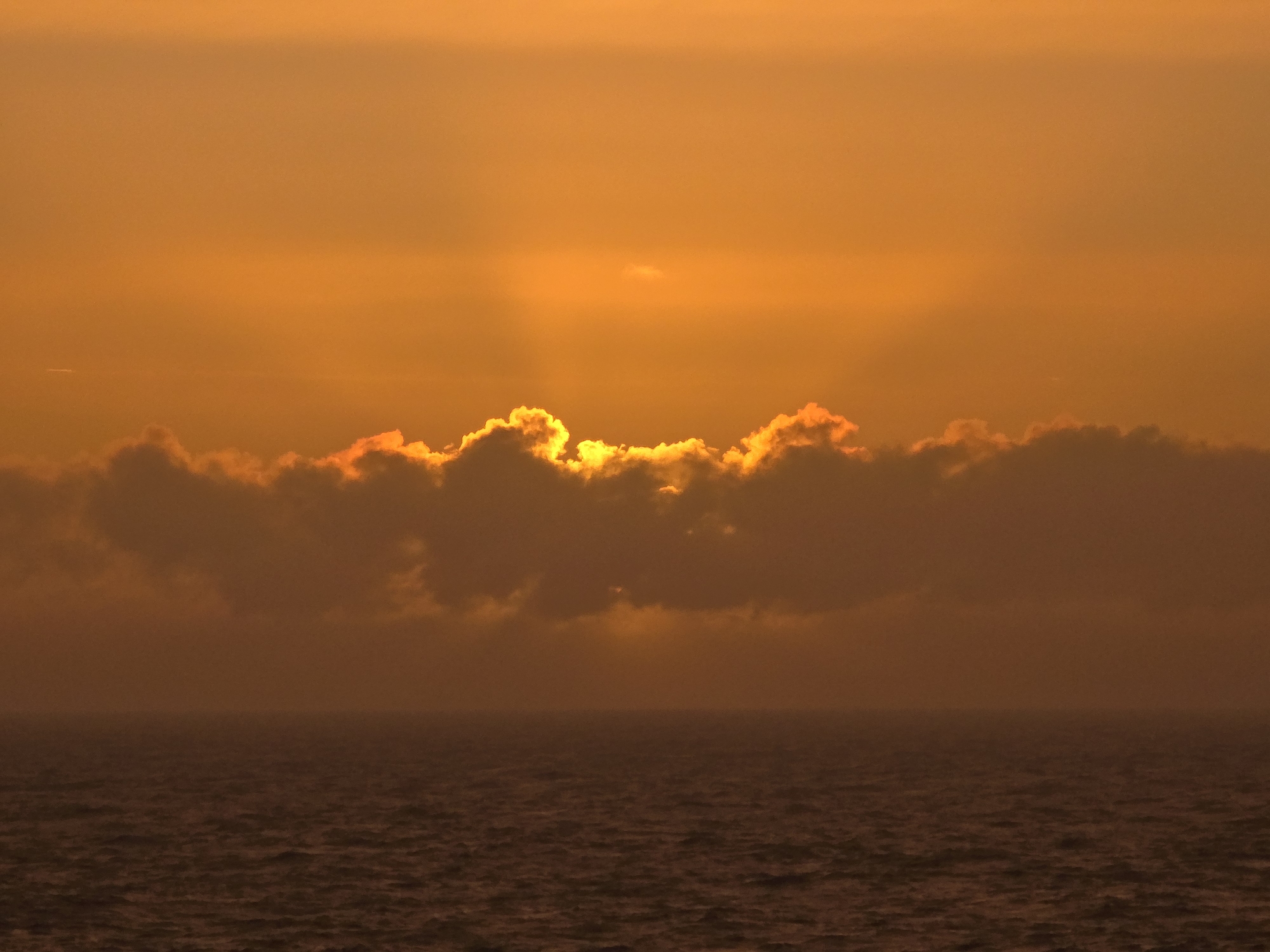 Sunset documented over North Sea waters with oil rig visible