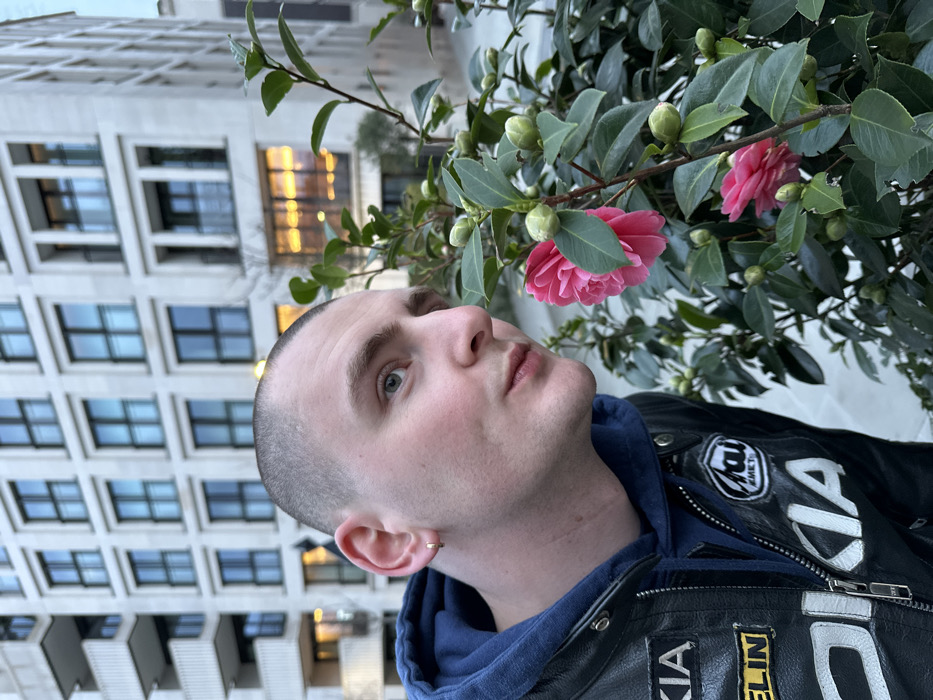 Man poses with blooming camellias in London