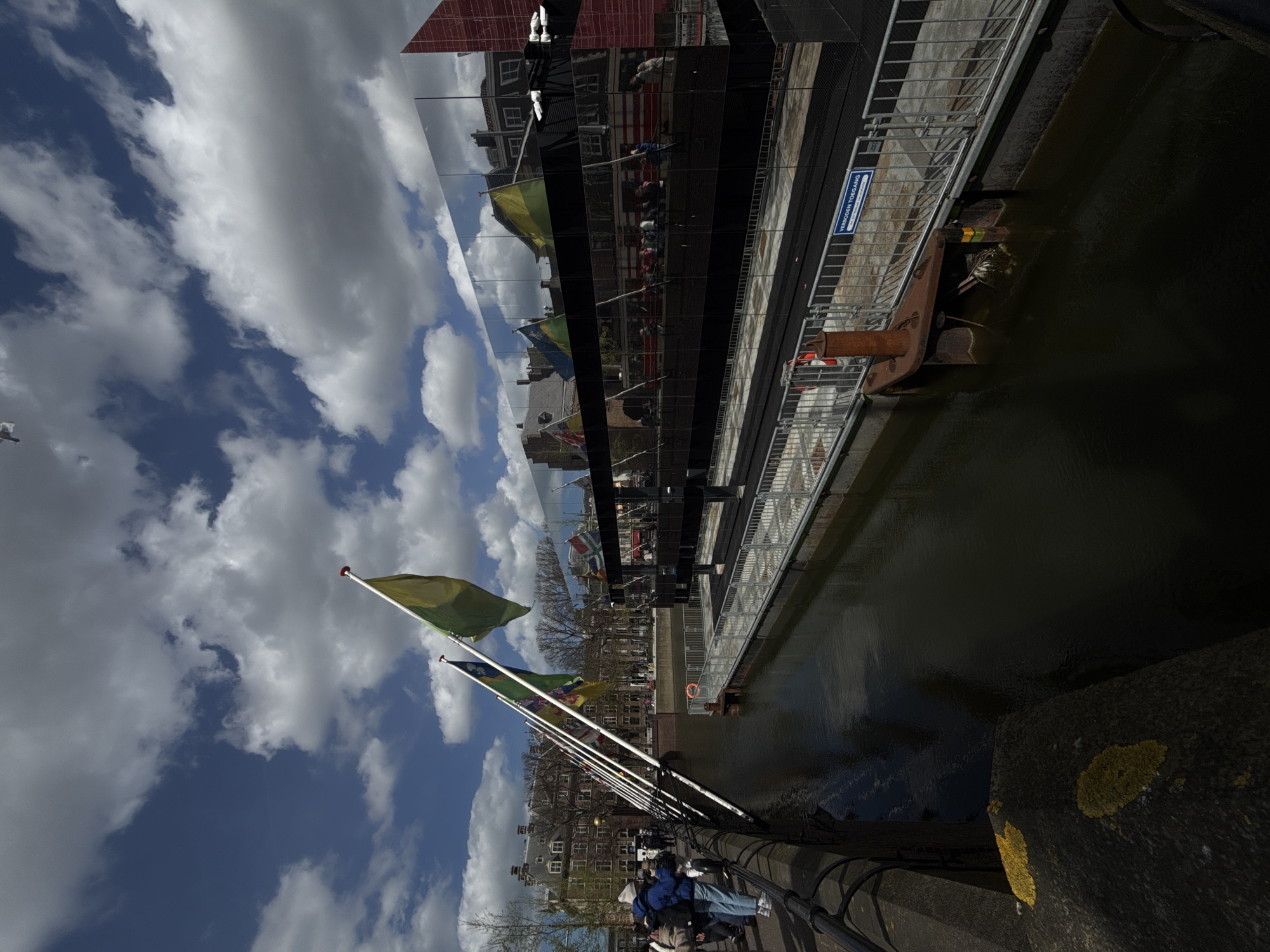 Canal scene documented in The Hague with pedestrians, flags